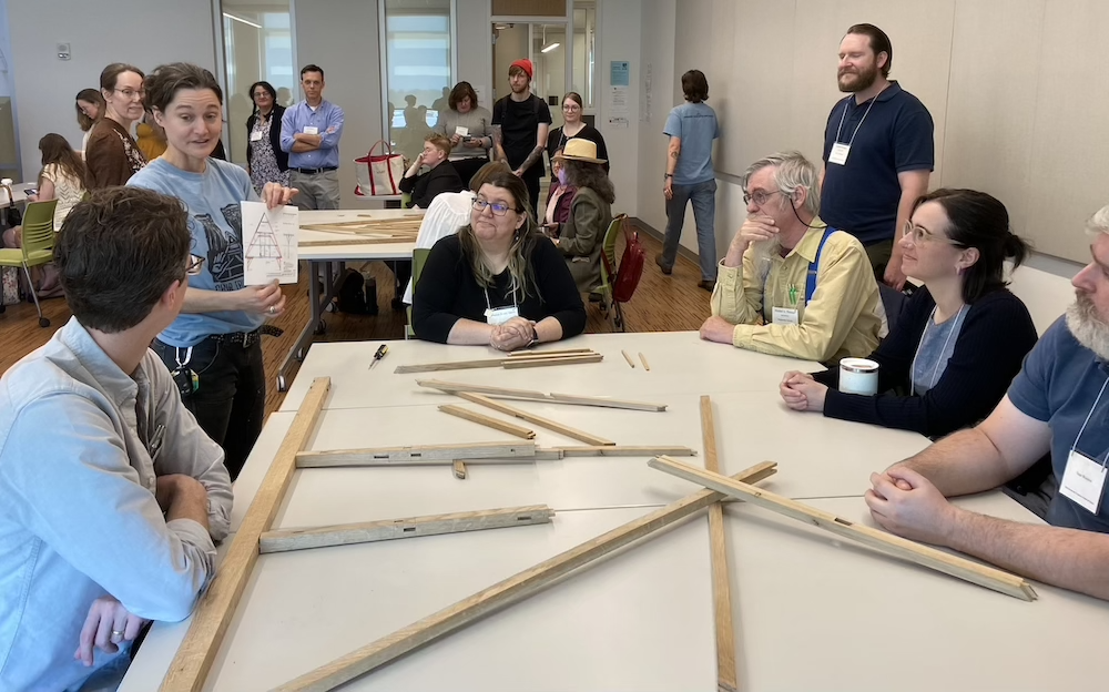 Five people sitting around a table listening to AVISTA Kalamazoo 2025 Workshop Instructions