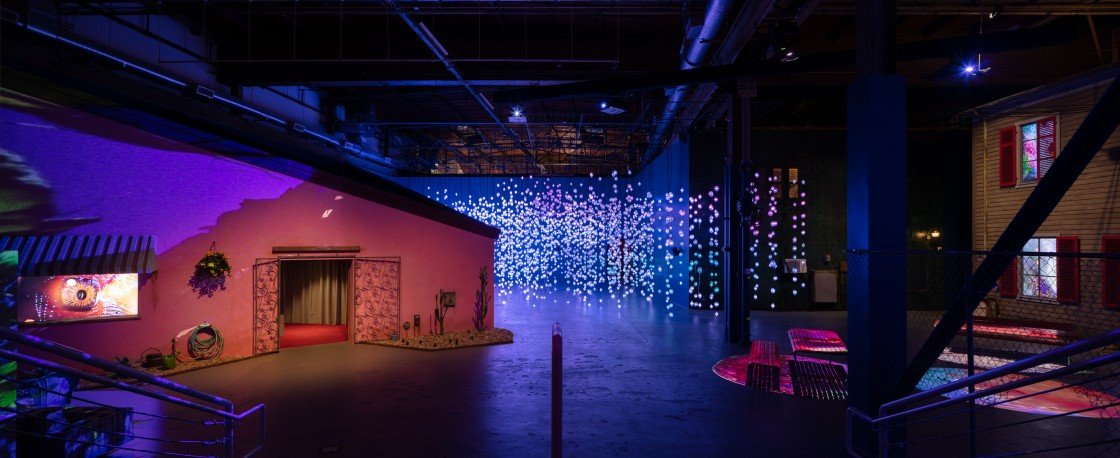 Single channel video (on the left) built into a facade. Pixel forest instillation in the center rear.