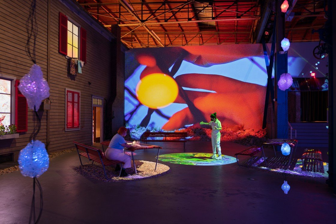 (On the left) five monitors mounted into the facsimile of exterior house windows.
(Center) Multiple projections mapped onto tables.
(Rear) Projection mapped video using four projectors install onto a steel truss.