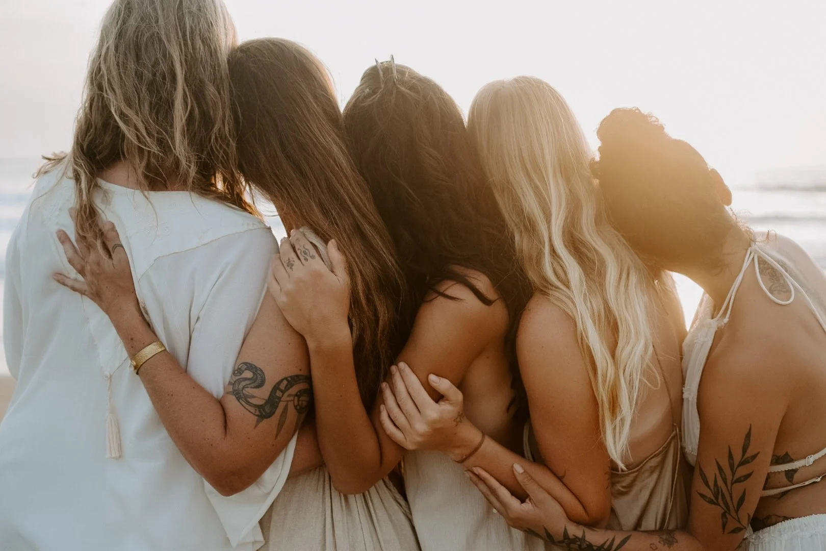 Kundalini Activation Facilitators holding each other on the beach in sisterhood.