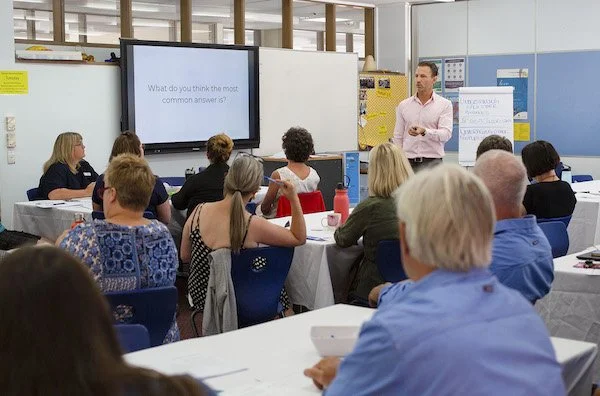 People sitting at tables in a workshop with Dan Kuss