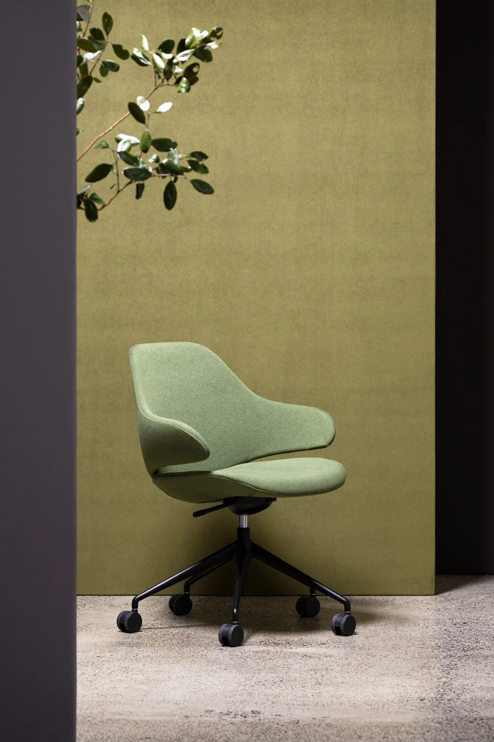 Modern green fabric chair photographed in a studio against a divider upholstered in green fabric, created for a commercial furniture shoot