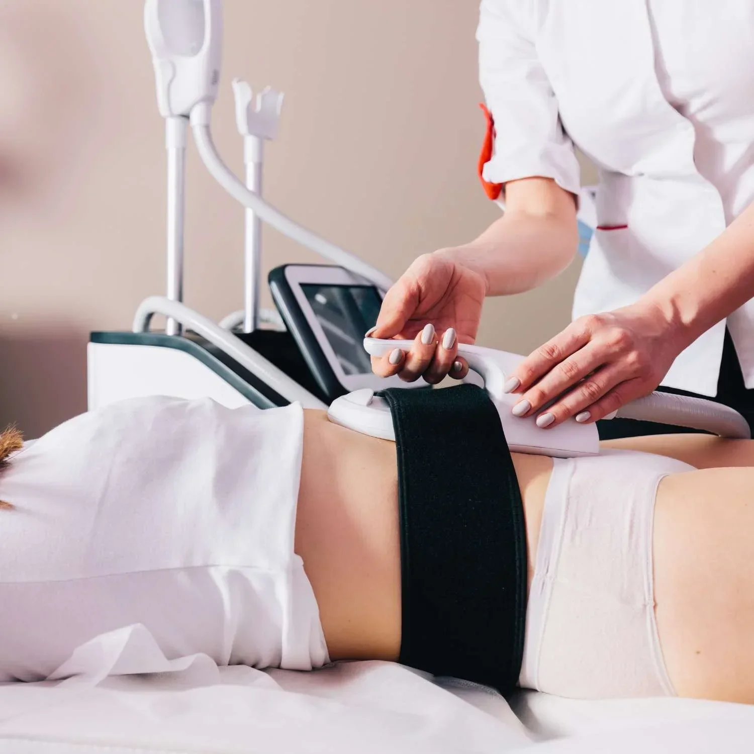 Medical professional performing an body sculpting procedure on a patient lying in a salon bed.