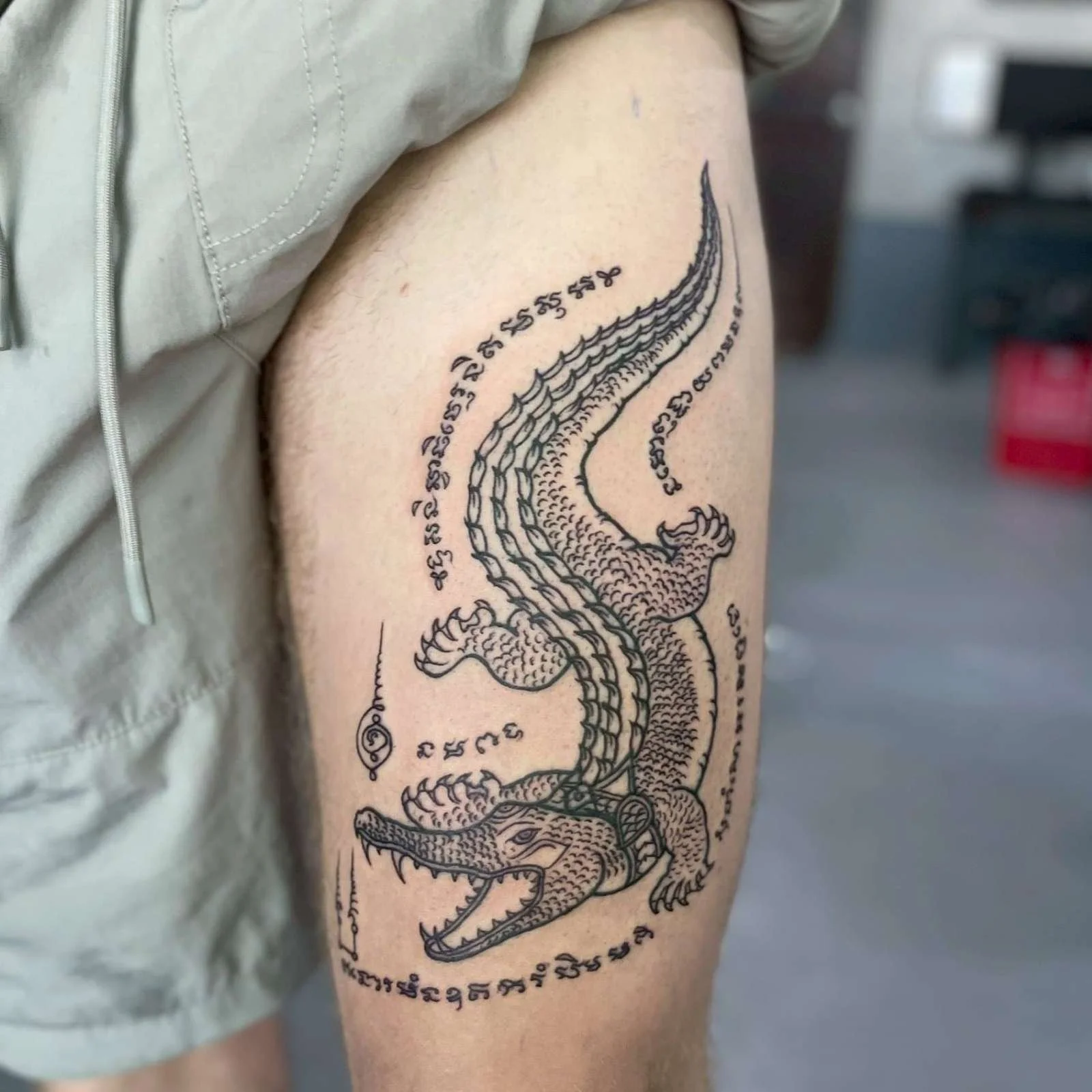 A man with a crocodile sak yant on hsi leg