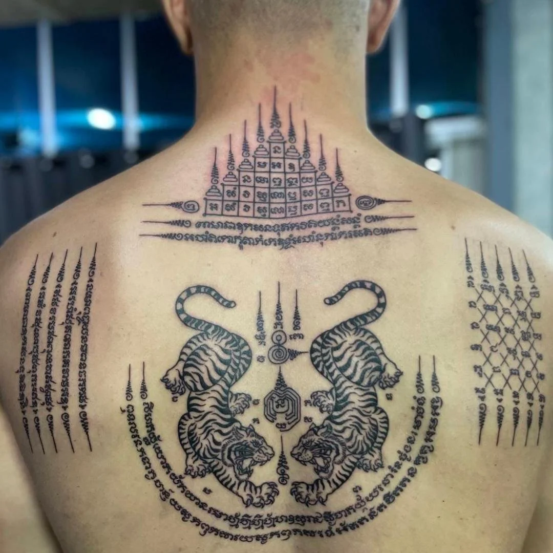 A man with a bamboo tattoo featuringGao yord, hah taew, chat pet and two tigers Sak Yant