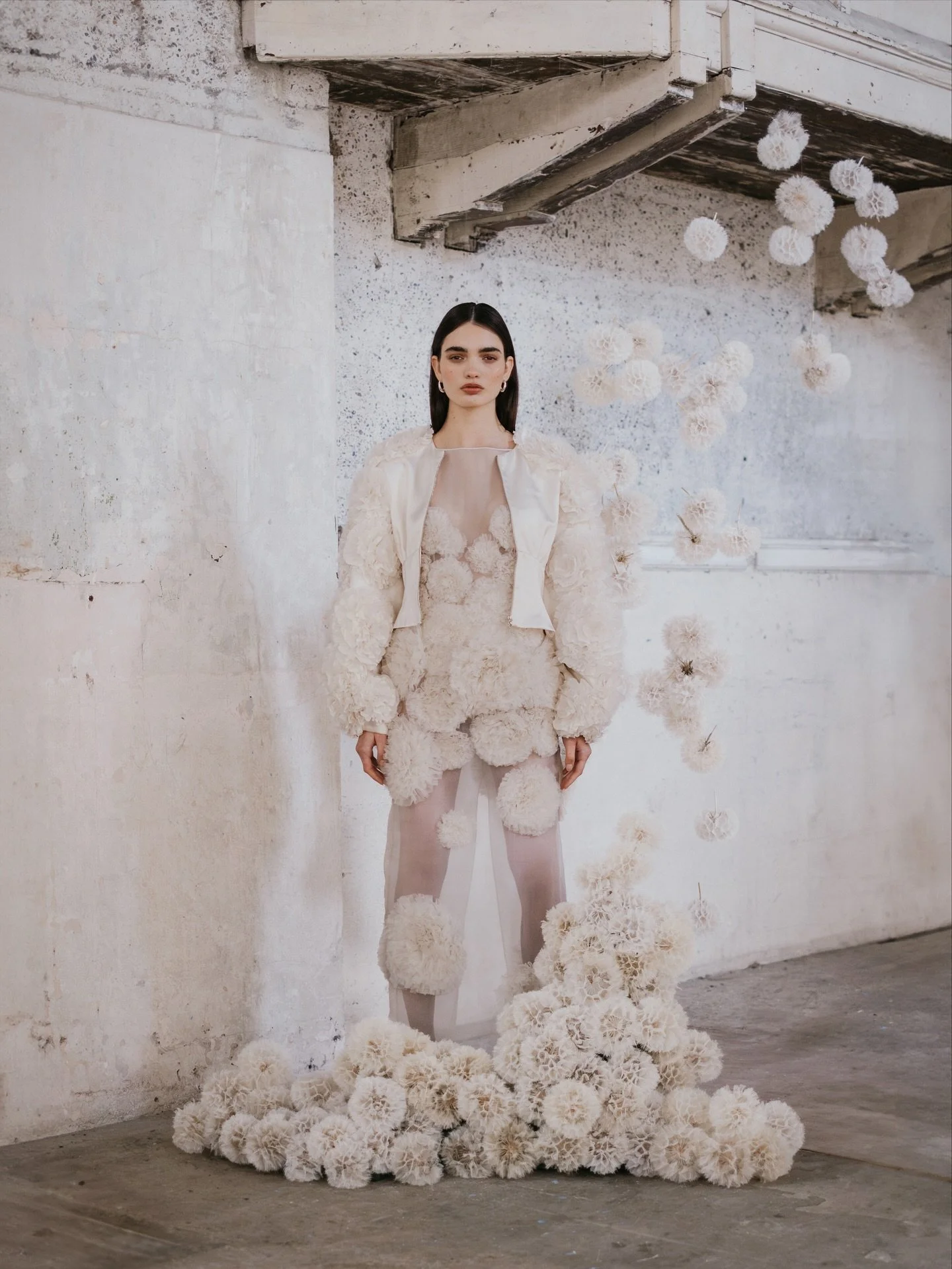 The DANDELION gown. Crafted from meters of ruffled silk organza that embody the dandelion&rsquo;s spherical form and unique layered textures.  Embroidered on a sheer silk column silhouette. This bridal gown strikes the balance between romanticism and