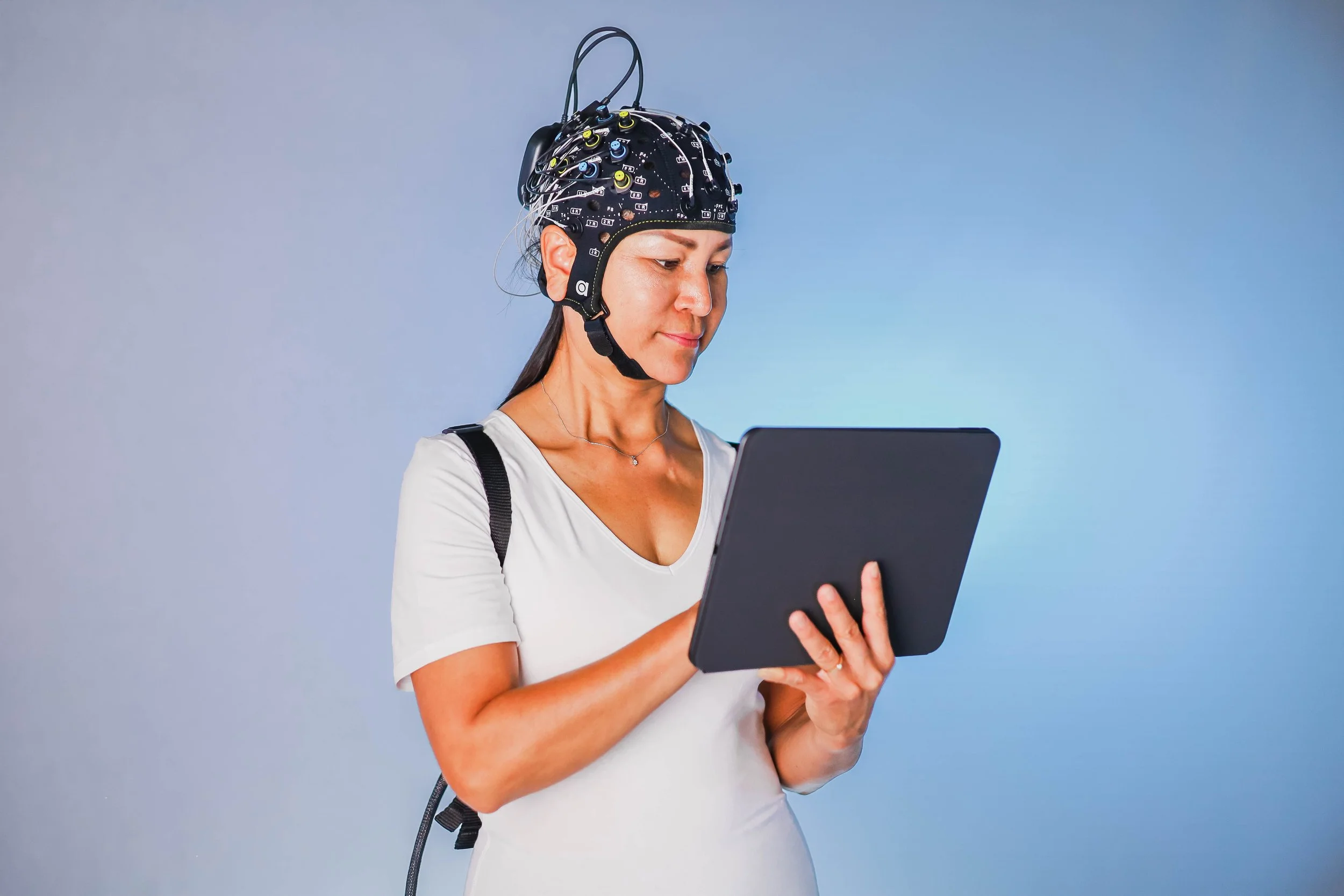 Image of a woman holding a tablet while wearing a multimodal fNIRS setup