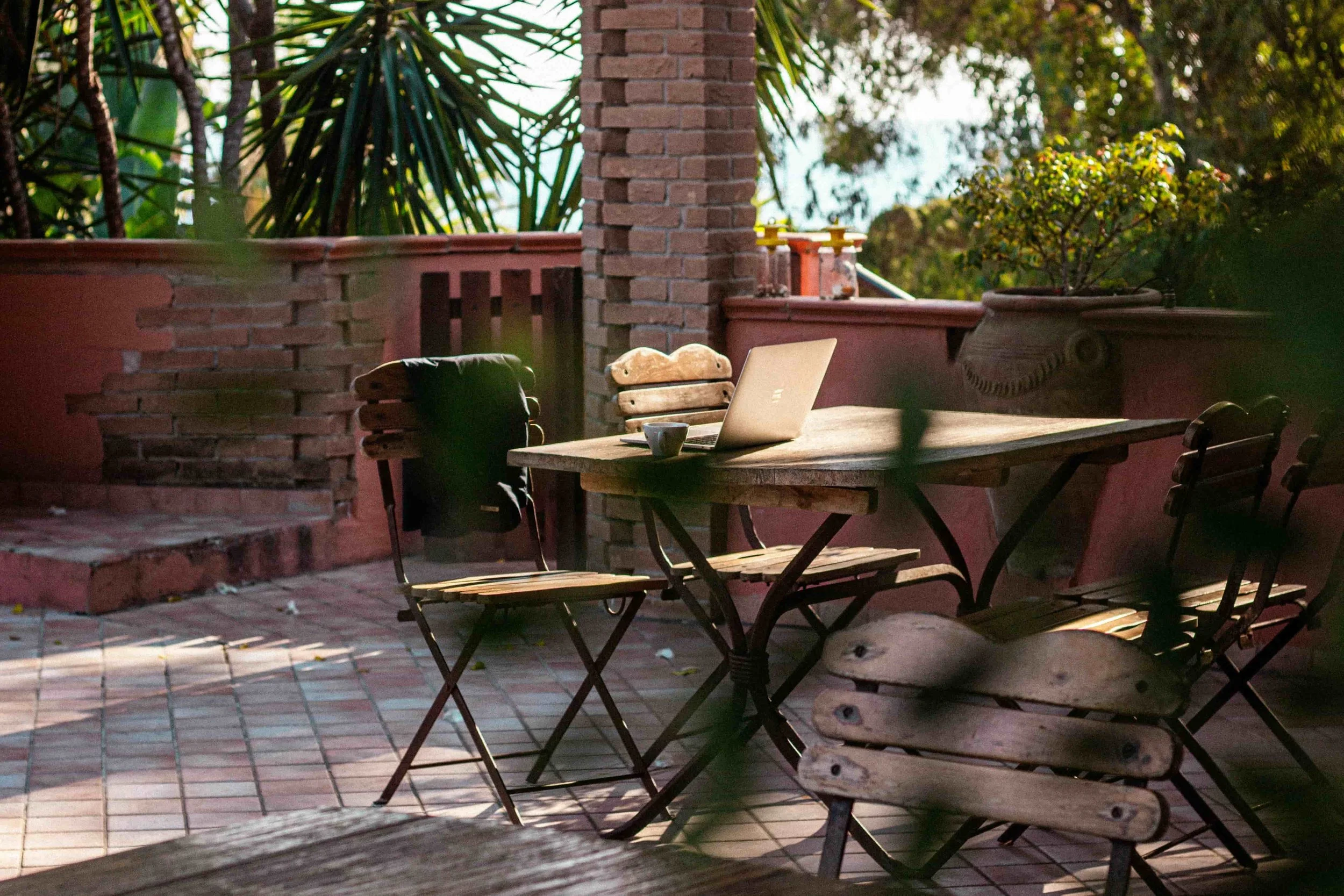 A pato with a table with a laptop and coffee on top