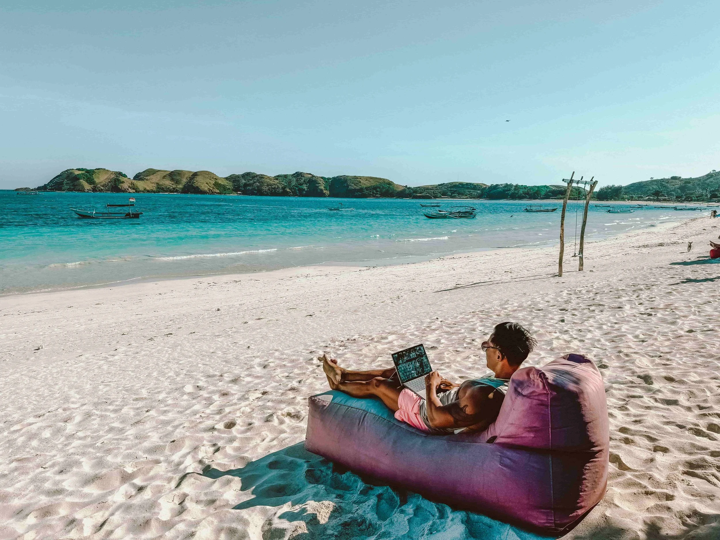 A guy on the beach with his laptop