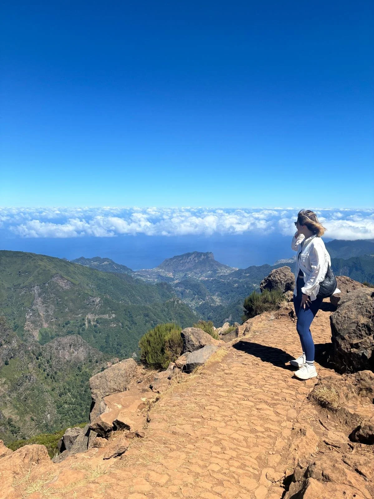 A woman looking over the clouds and mountains at a viewpoint on Madeira