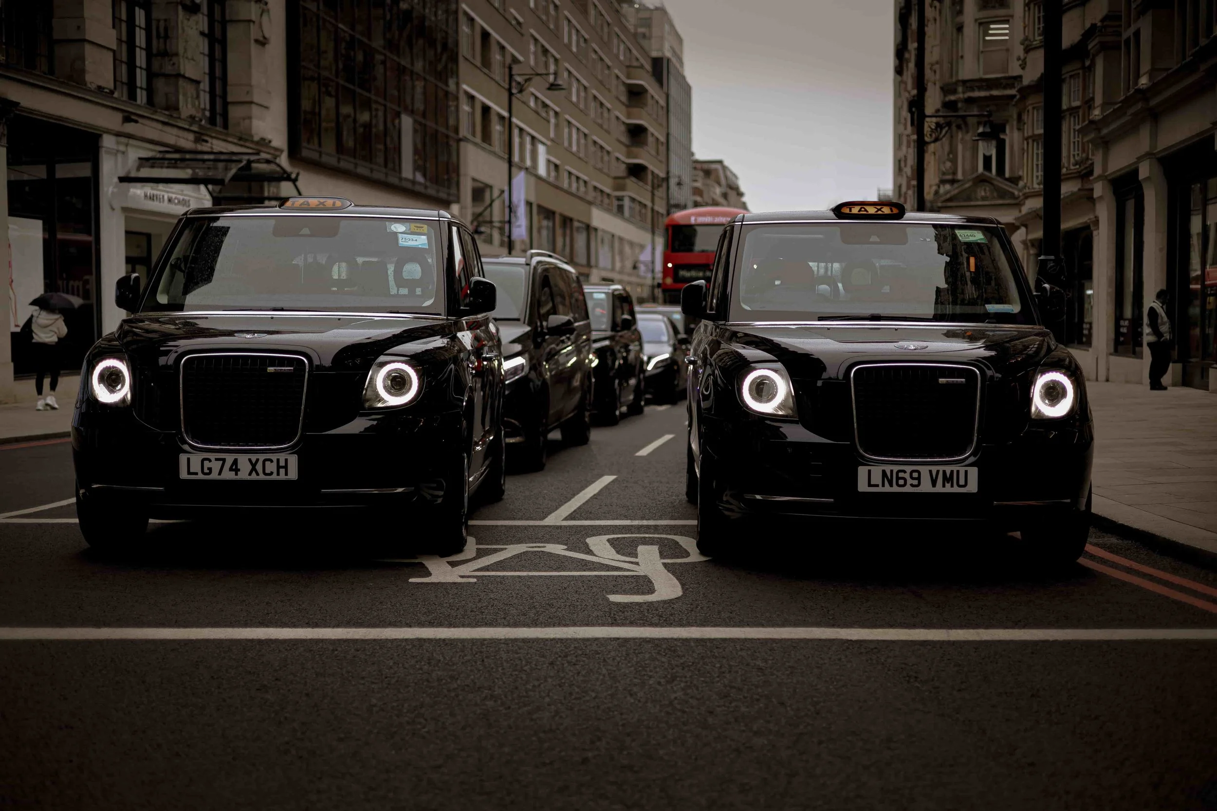two black taxison a street