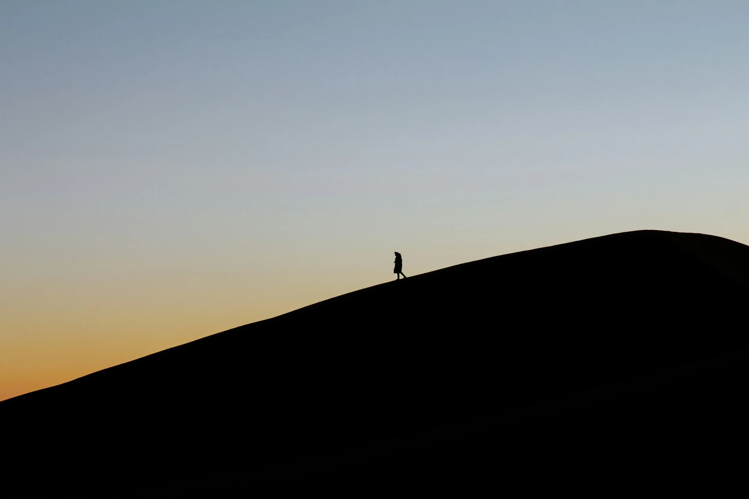 A person in the distance on a mountain with the blue sky