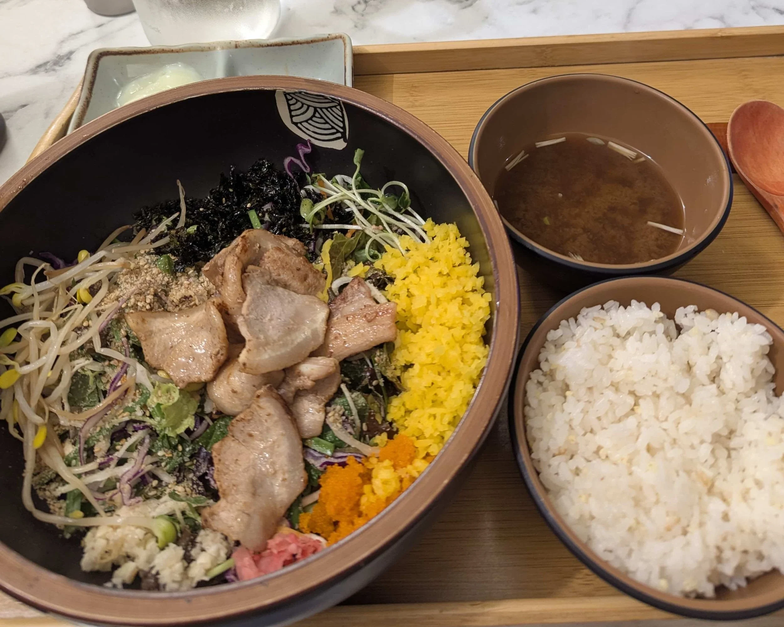 A bowl of bibimbap with rice on the side