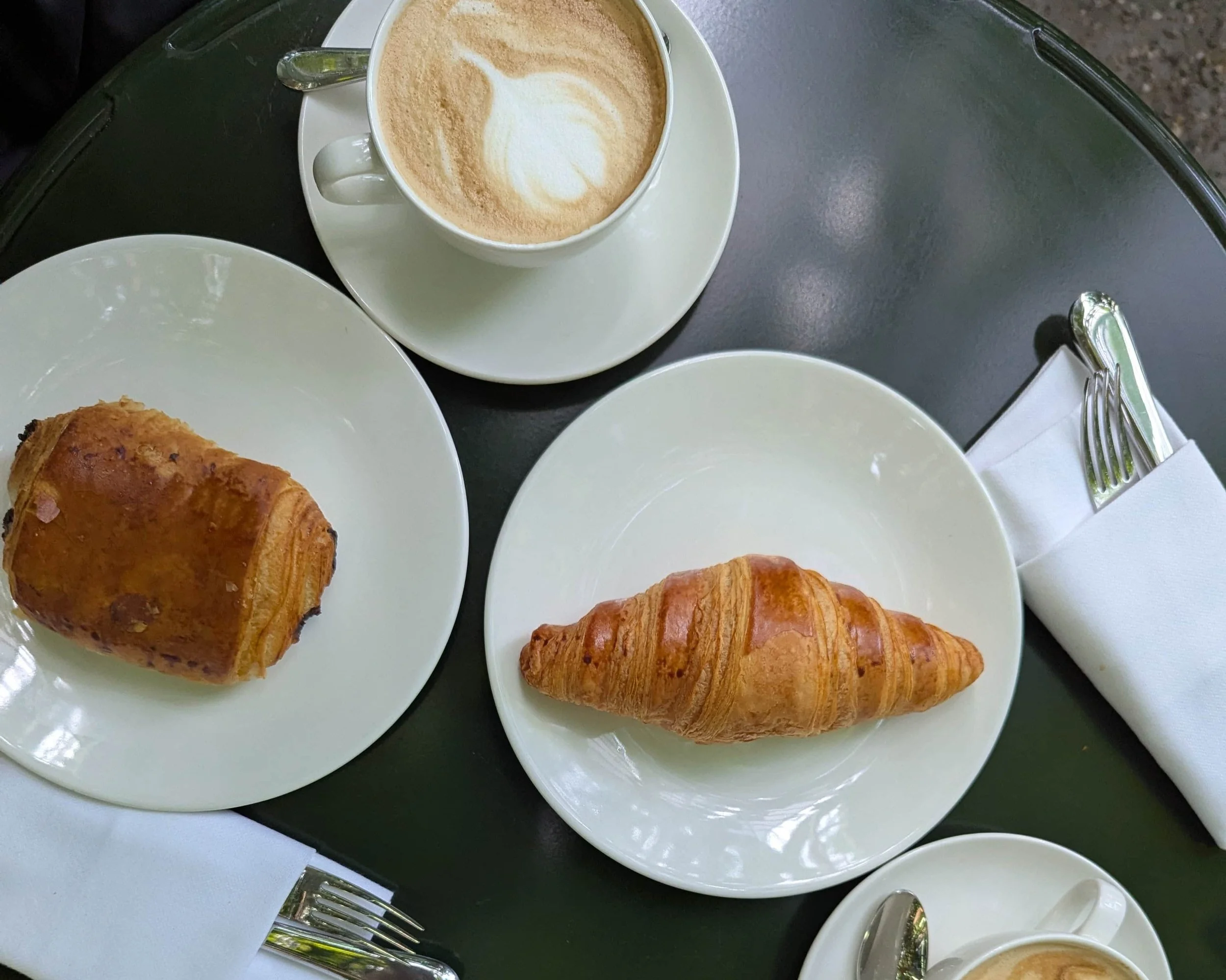 A pain au chocolat, a croissant and coffees on a table