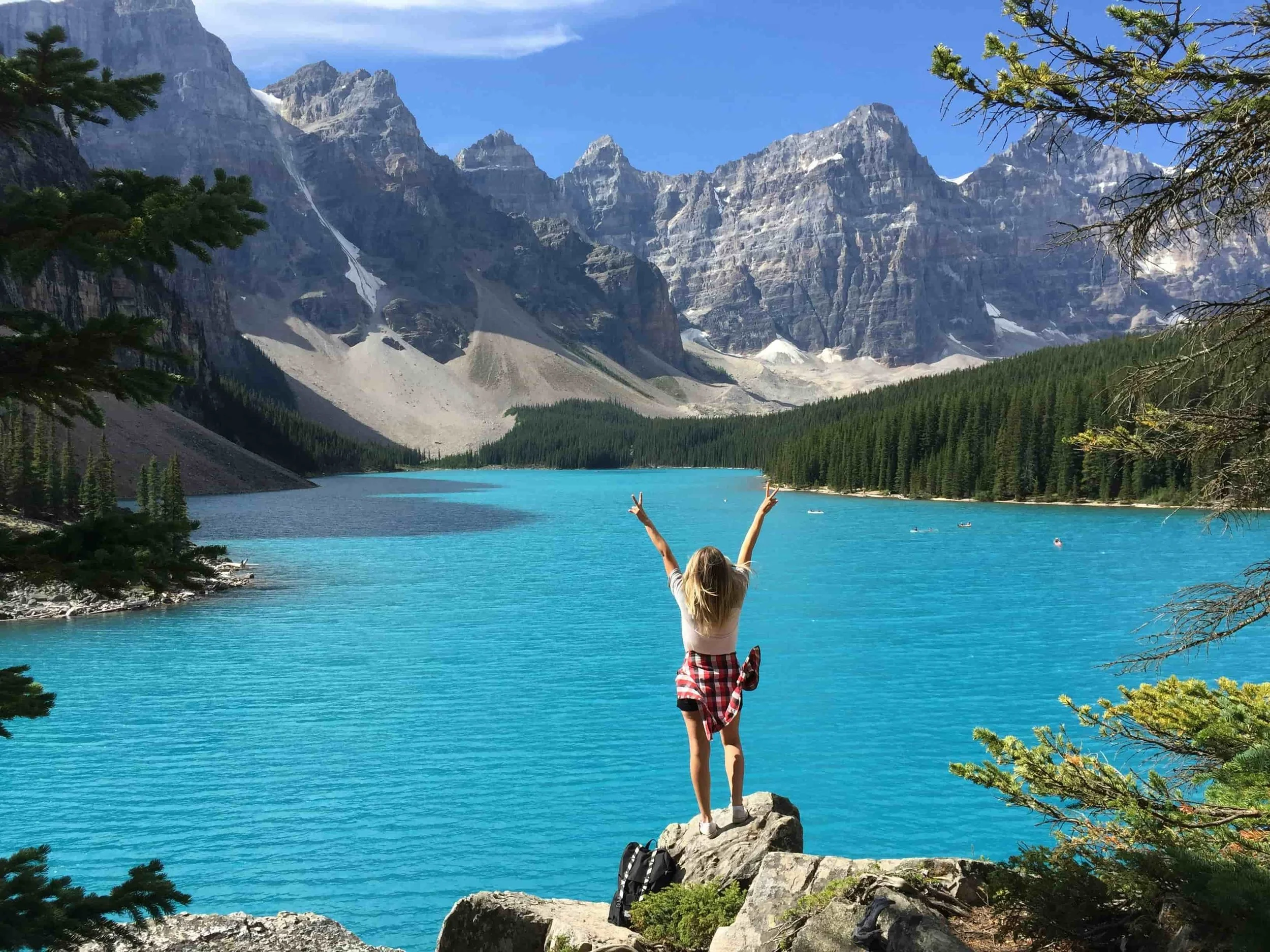 Woman standing on a rock overlooking a lake and mountatins in Banff National park