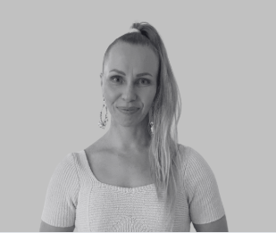 Black and white portrait of a smiling woman with shoulder-length wavy hair, wearing a dark blazer with buttons.