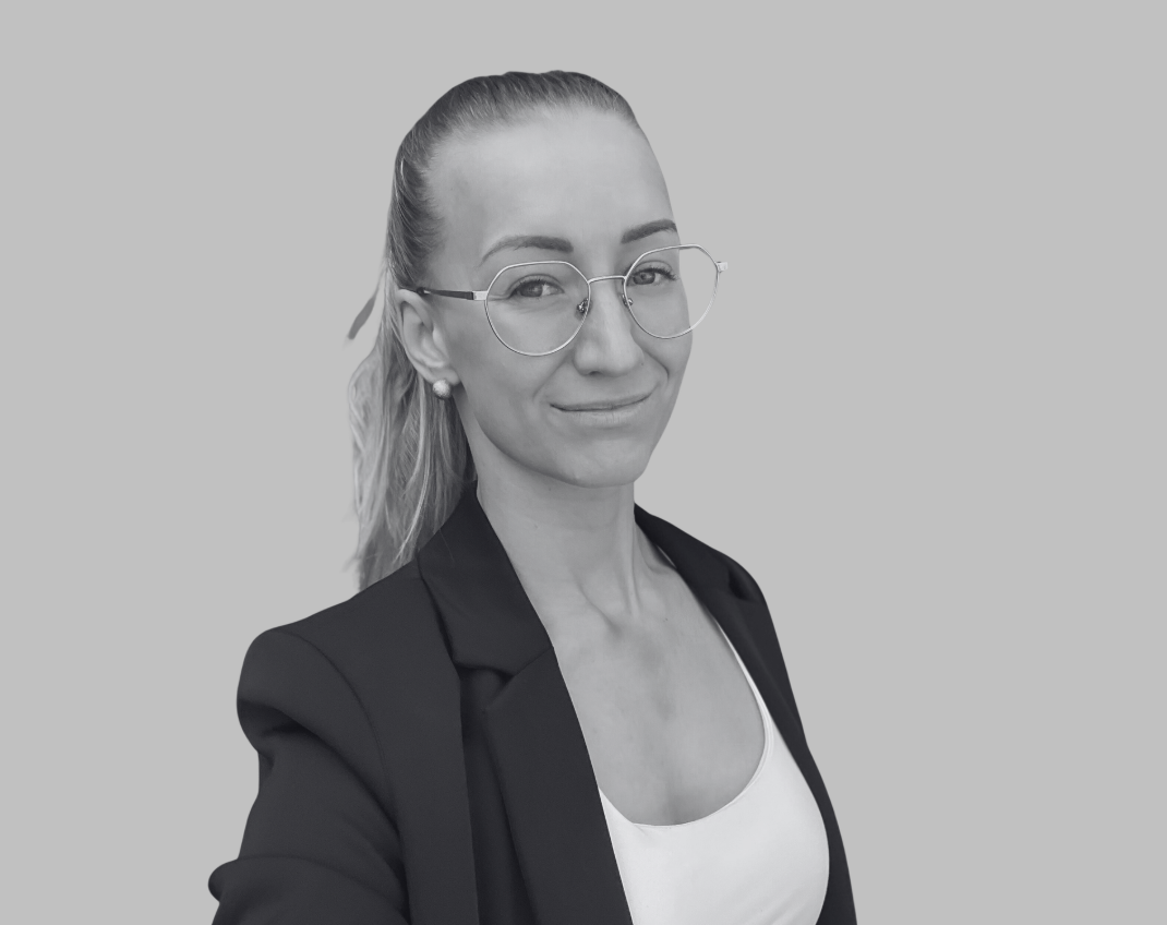 Black and white portrait of a smiling woman with shoulder-length wavy hair, wearing a blazer, posed against a plain background.