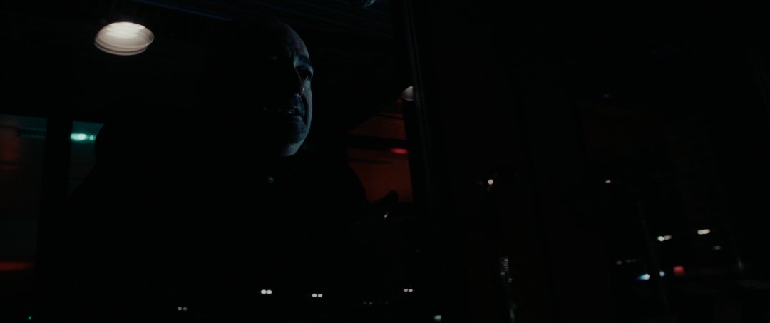 dark scene with a person silhouetted against a dimly lit background