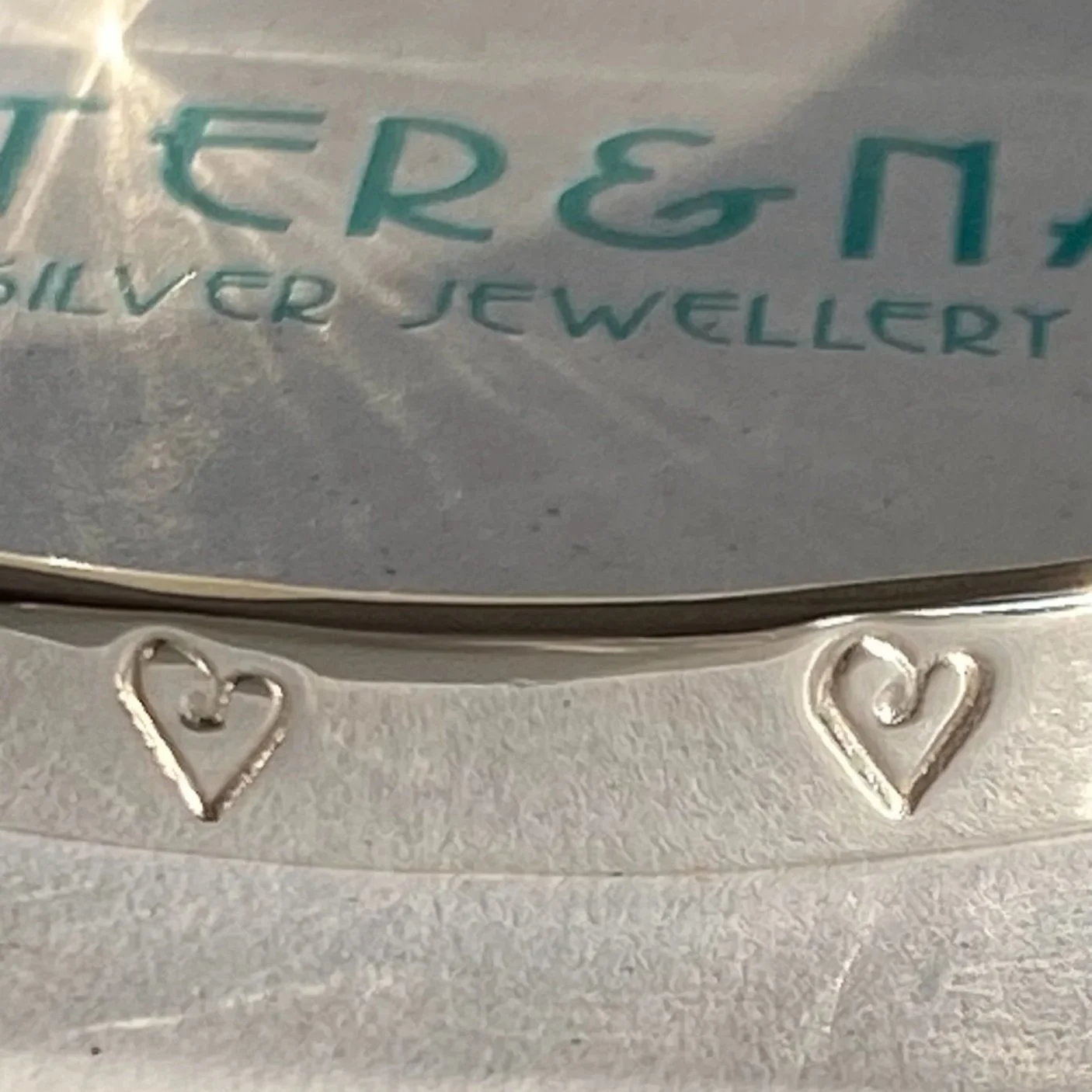 Close up of hand stamped and handcrafted sterling silver signature bangle.