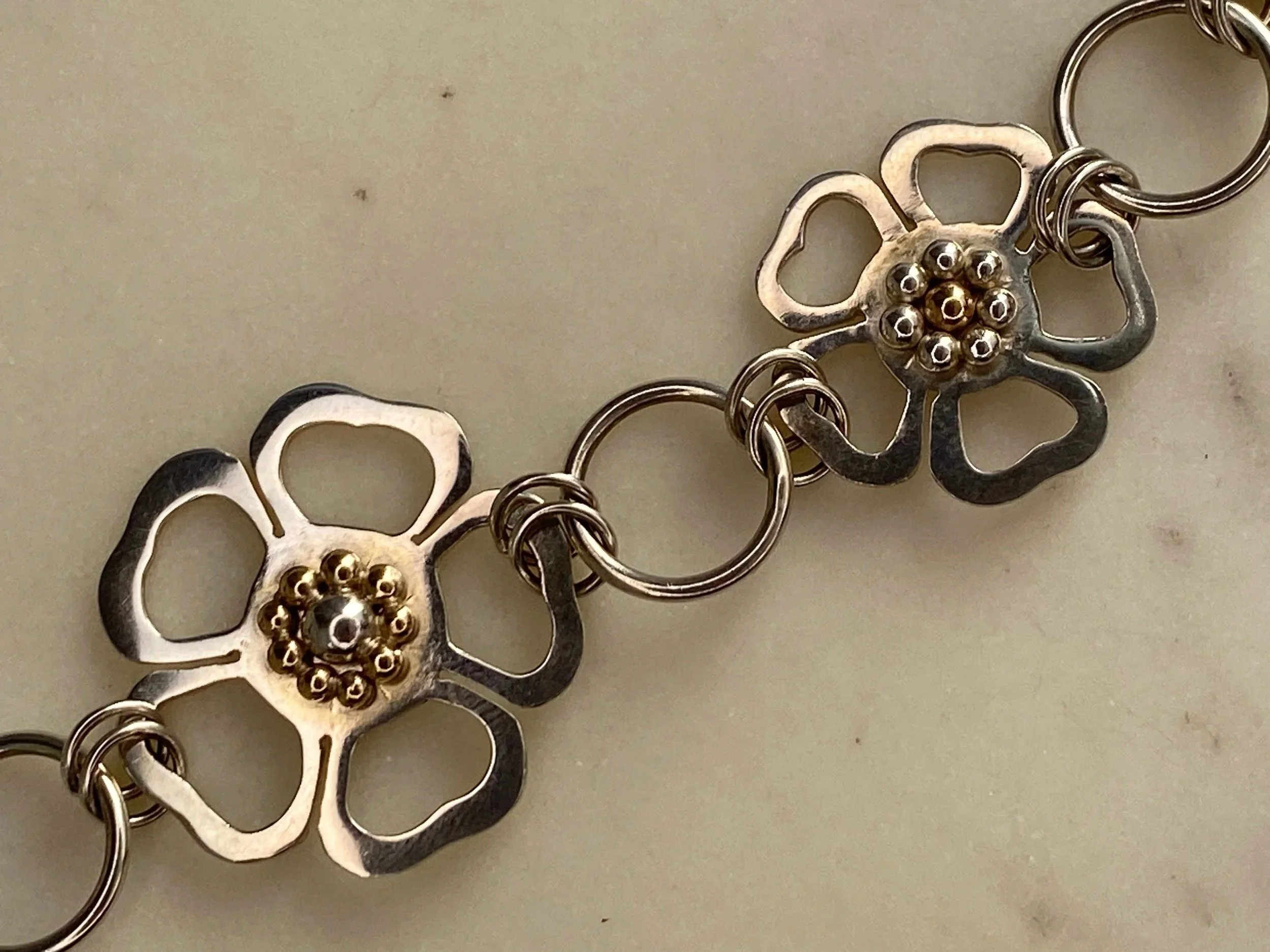 One of a kind, handmade sterling silver and nine carat gold flower bracelet. Made by Walter and Nancy Jewellery.