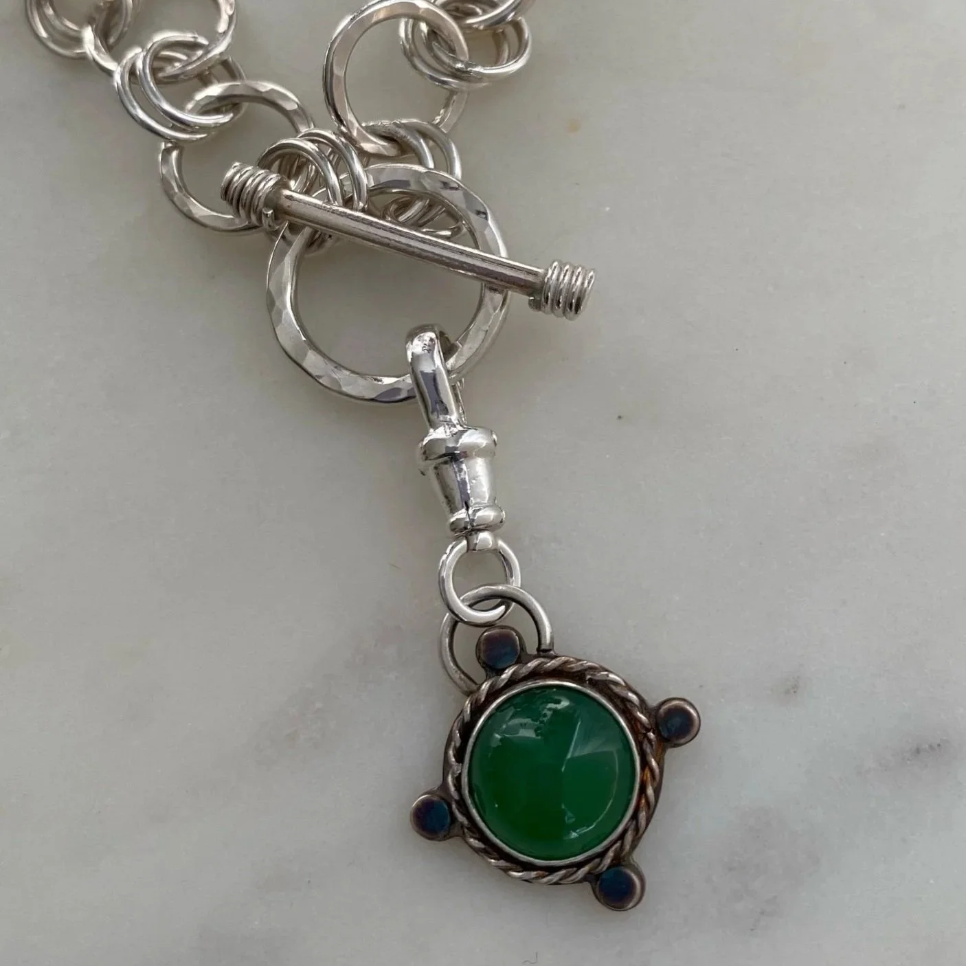Walter and Nancy Jewellery's handmade, sterling silver and green onyx necklace charm shown attached to a chunky chain.