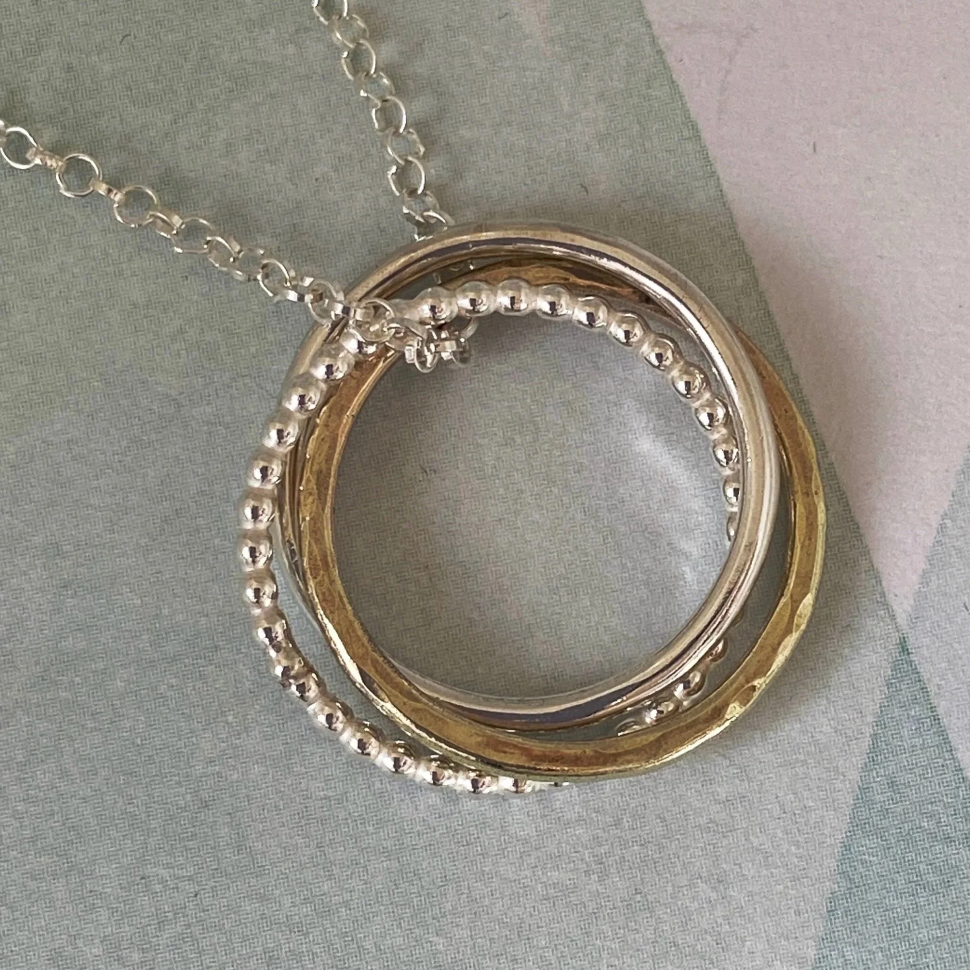 Handcrafted from sterling silver jewellery and 9ct gold by Walter and Nancy Jewellery in Surrey, UK. Three linked rings each with a different finish.