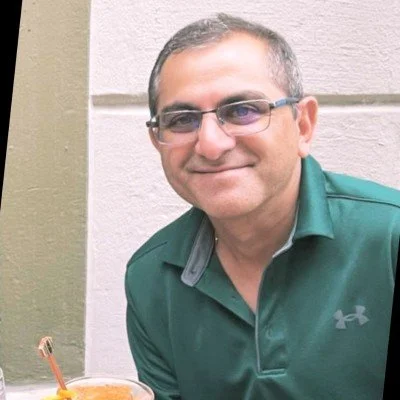 A portrait of a woman with short black hair, wearing a navy blue top, smiling against a gray background.