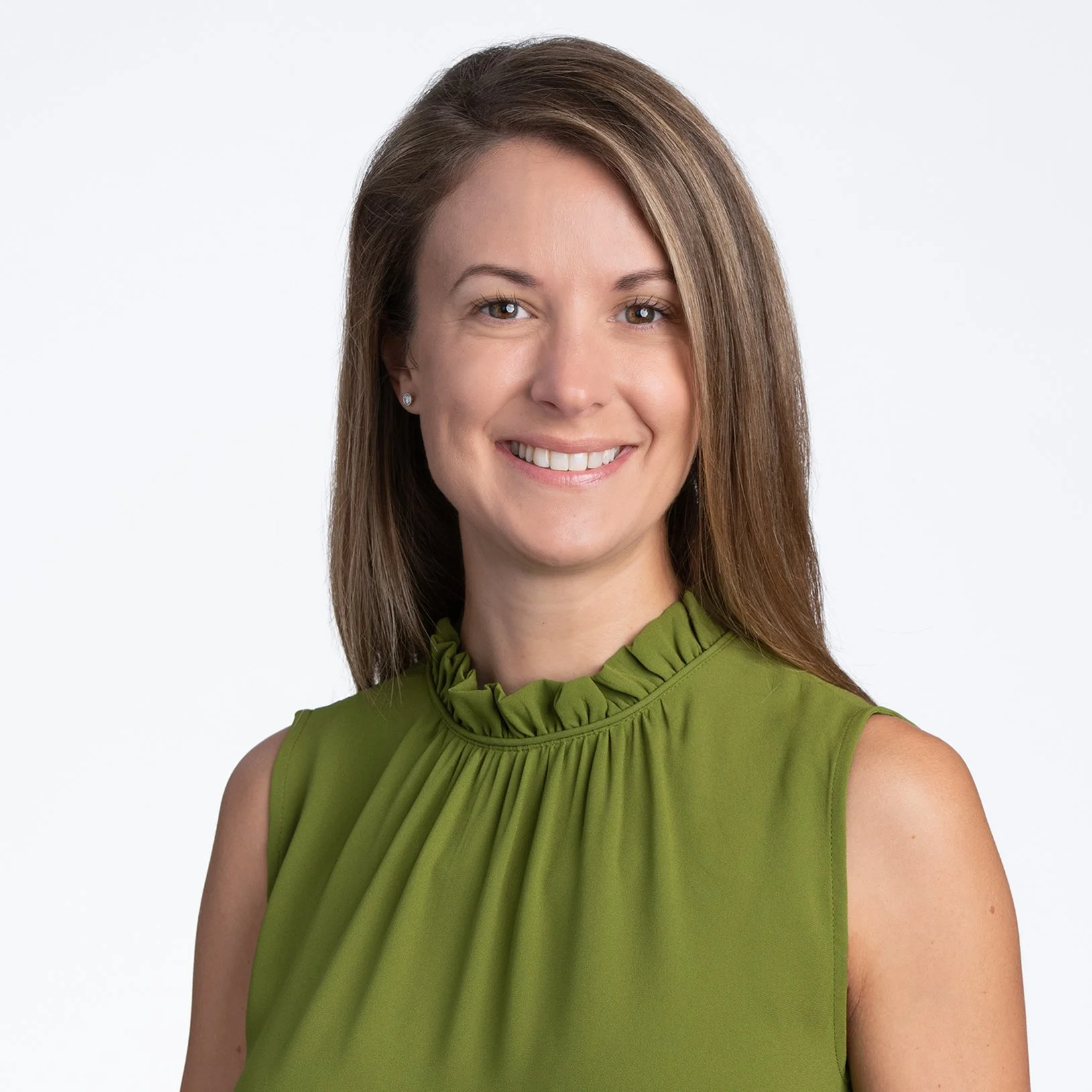 A smiling woman with brown hair wearing a sleeveless green blouse.