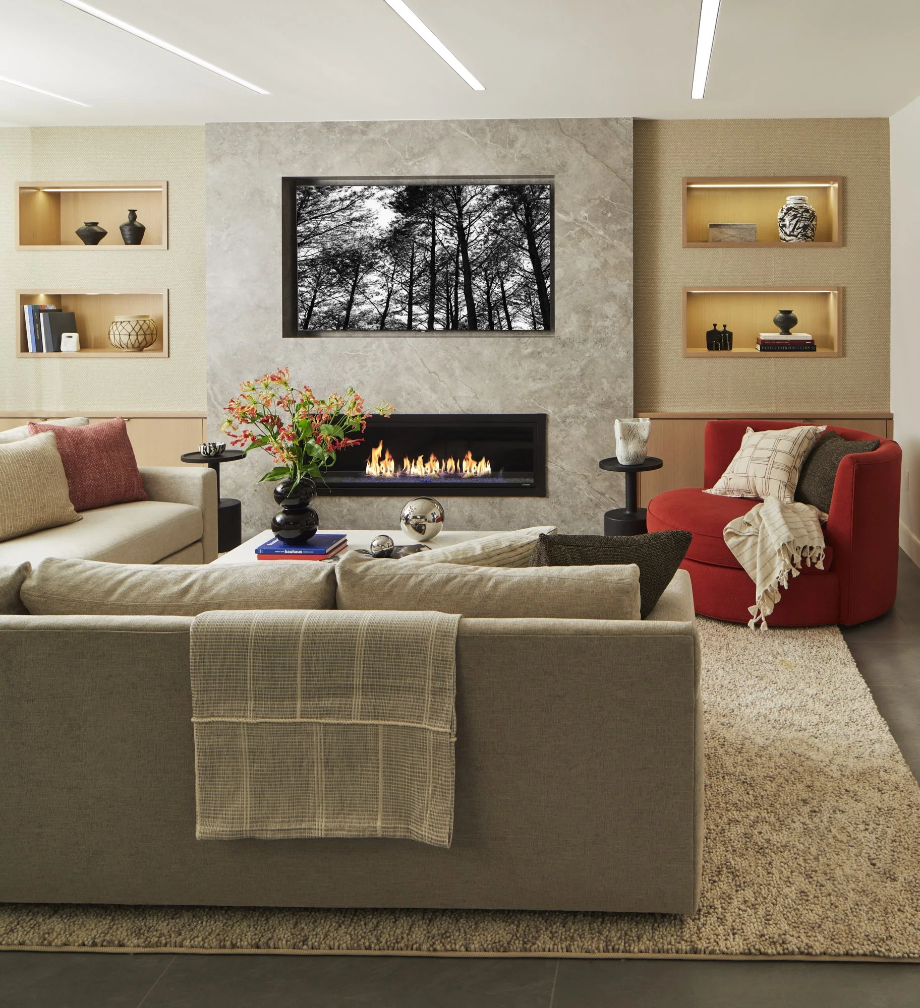 Family movie lounge with a sectional sofa, red armchair, stone fireplace, television, built-in shelving, and a large area rug.