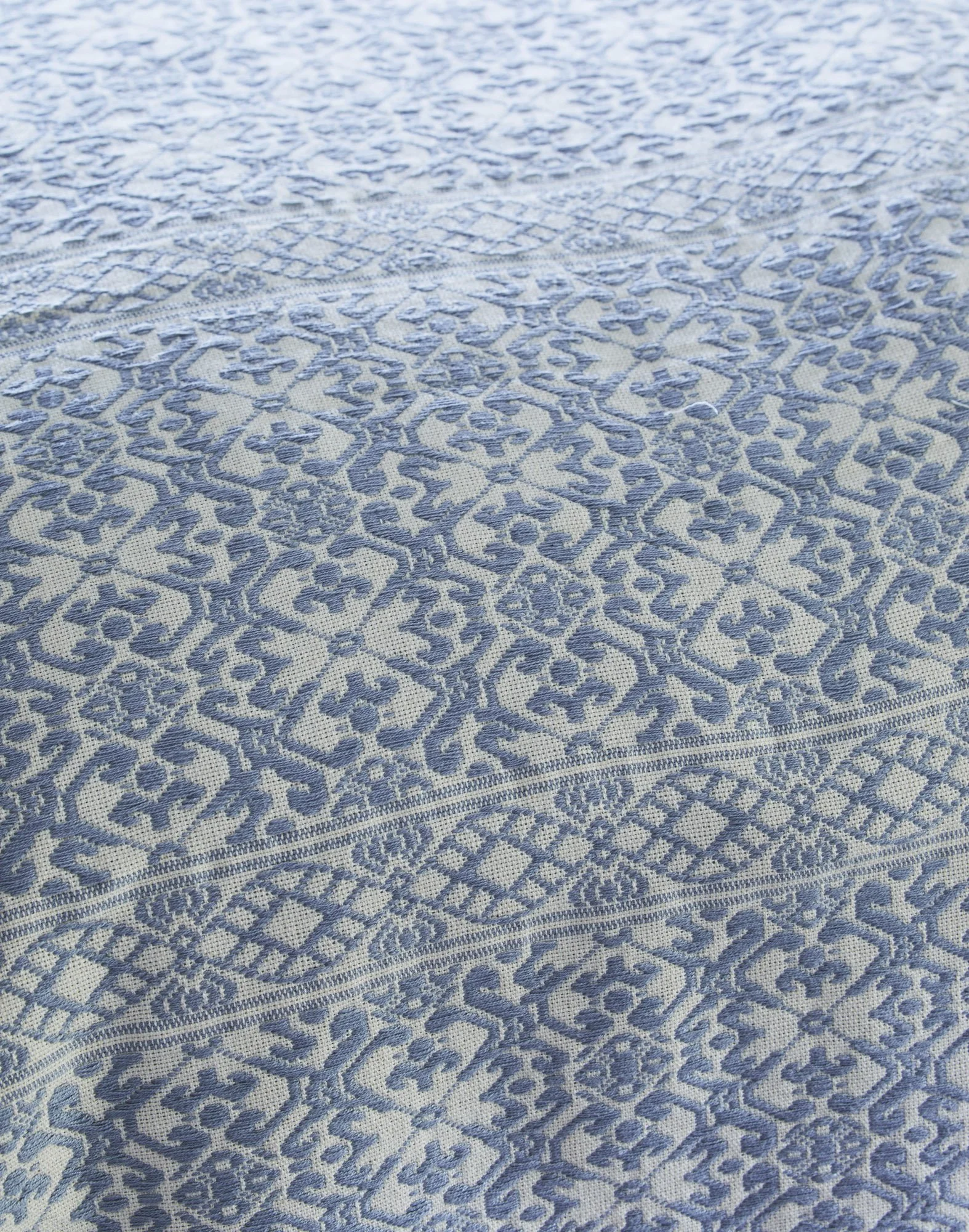 Close-up of a blue-and-white woven textile with intricate geometric and floral motifs.
