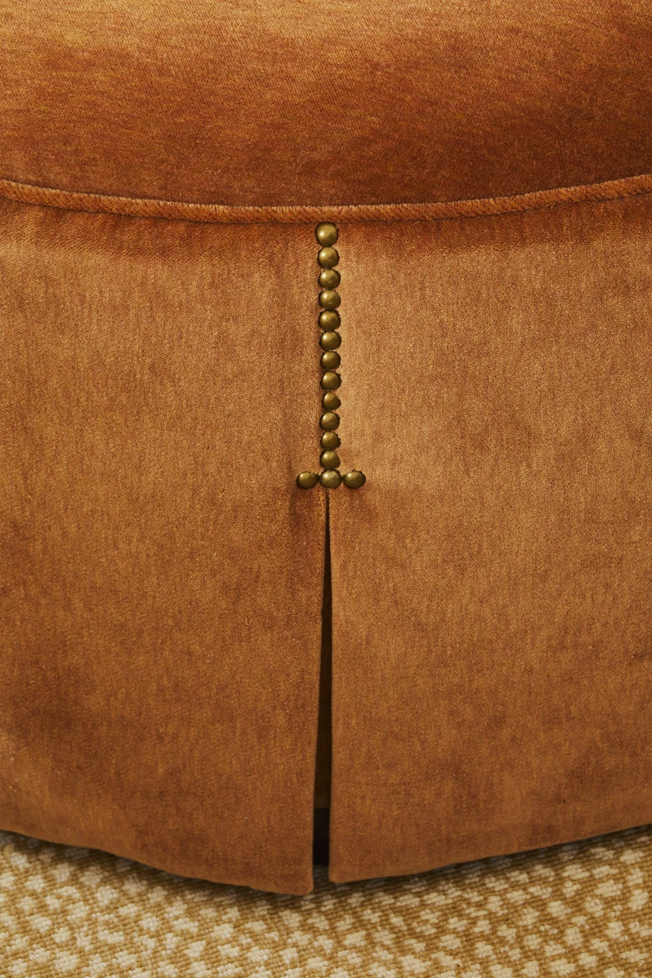 Close-up of tan upholstery finished with decorative brass nailhead trim.