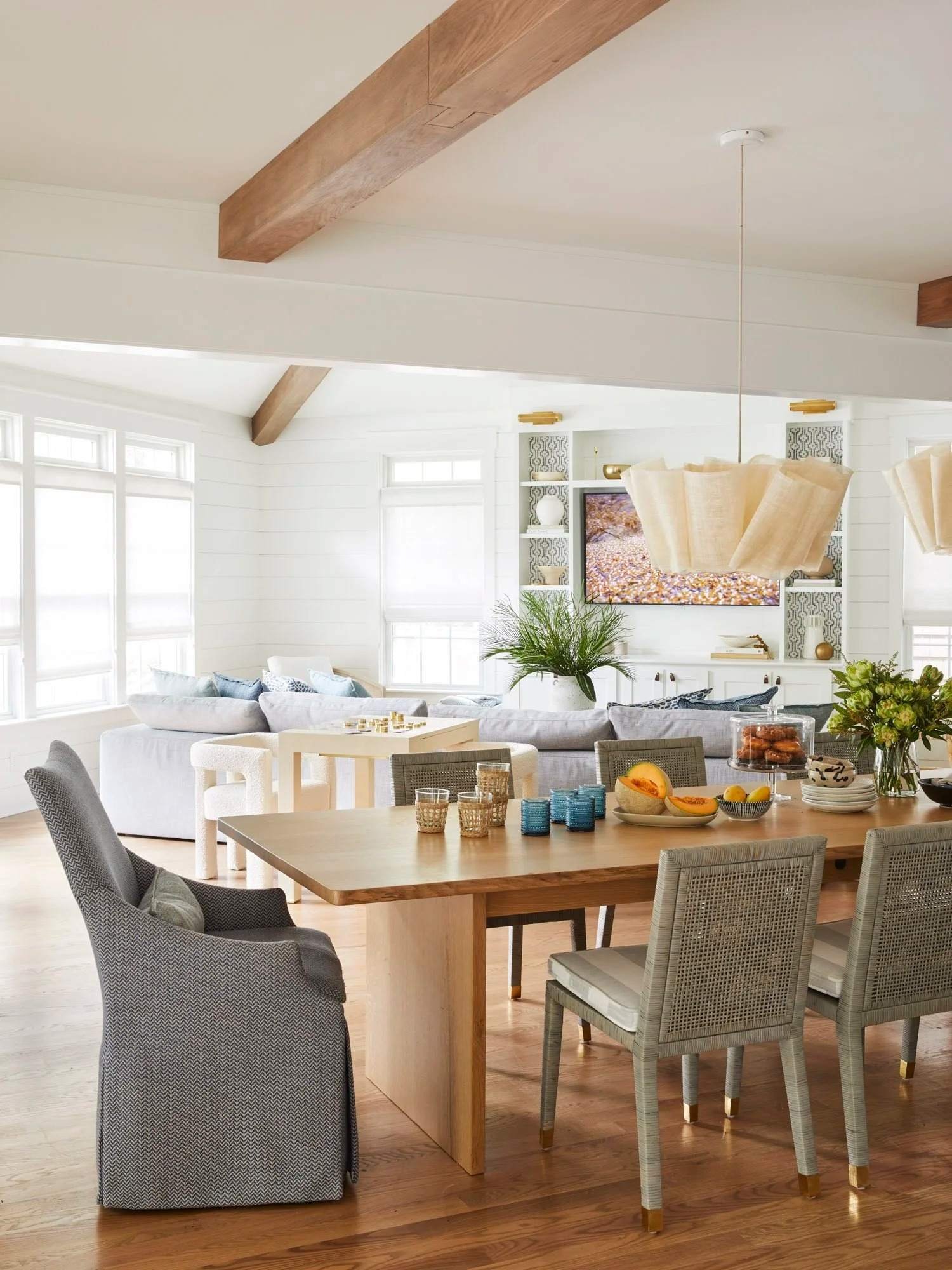 Relaxed Rehoboth Beach living room with a gray sectional, exposed wood beams, and a circular chandelier from The Beach House portfolio.
