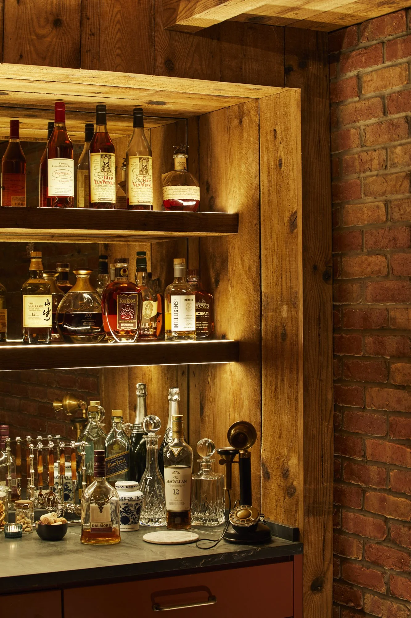 Hidden Bethesda speakeasy bar with reclaimed wood shelving, whiskey bottles, glassware, and a vintage telephone.