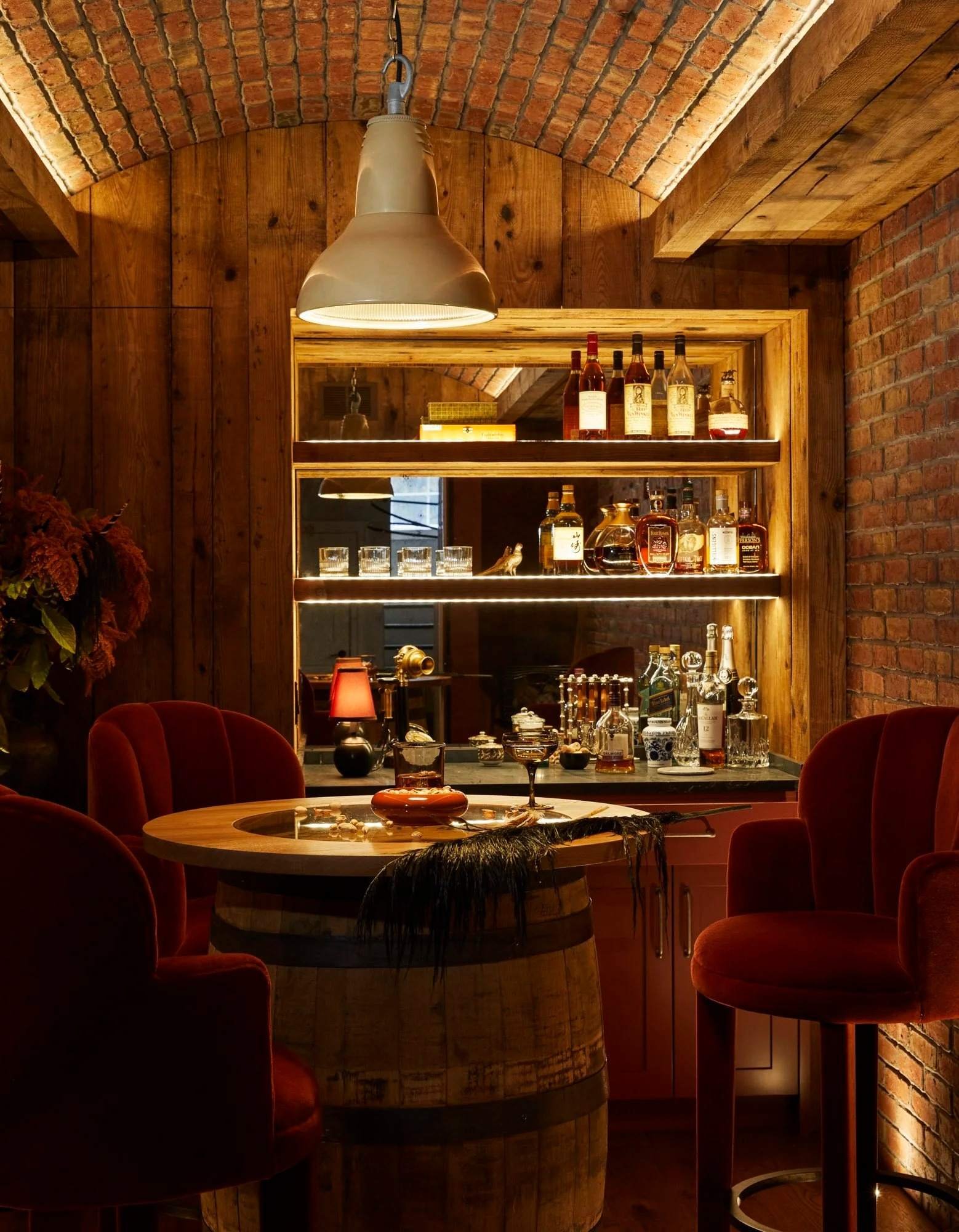 Bethesda speakeasy with a brick-vaulted ceiling, barrel table, and red velvet chairs from the Stepping Into the Past portfolio.