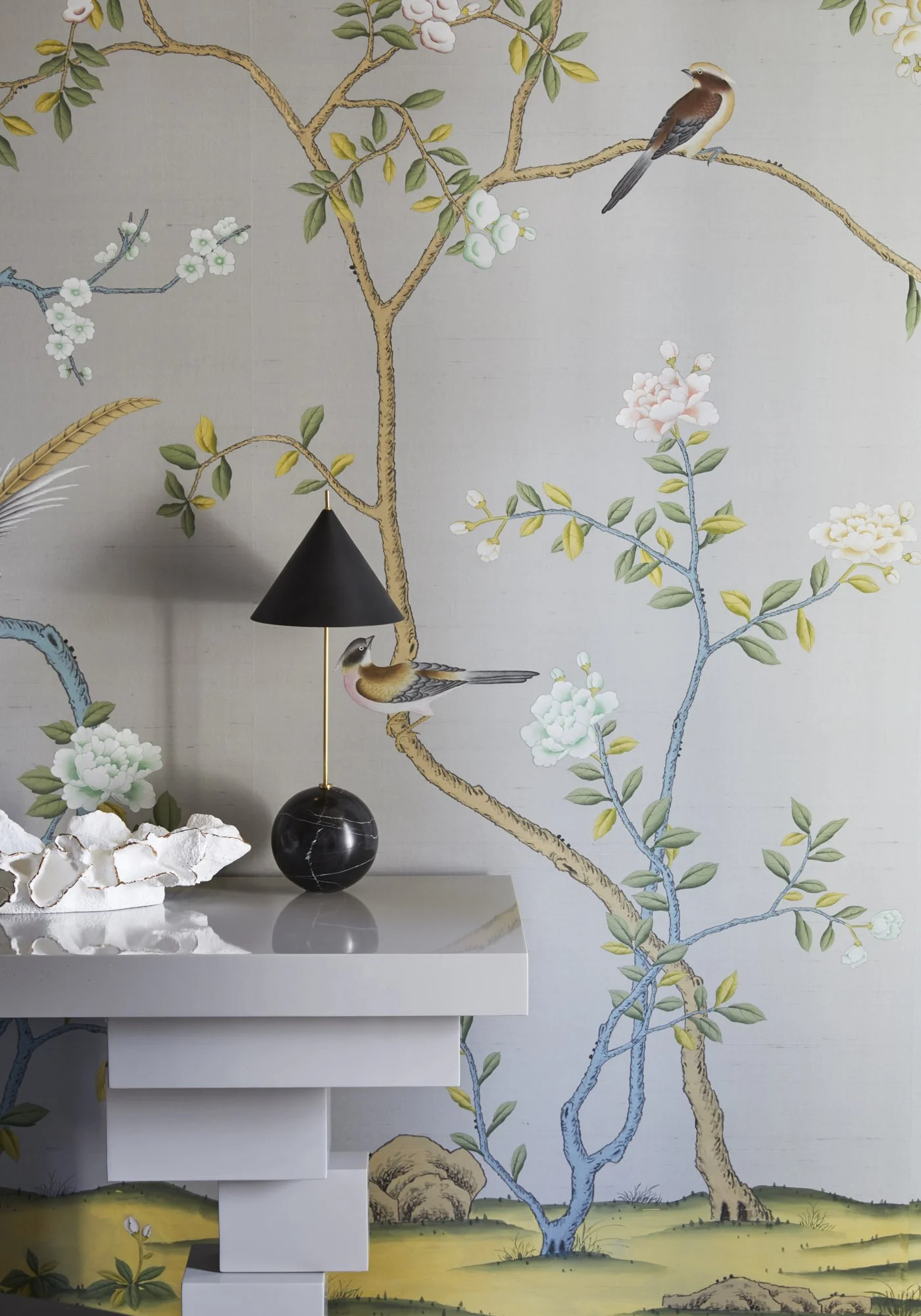 Black lamp with a marble base displayed against wallpaper featuring birds and flowering branches.