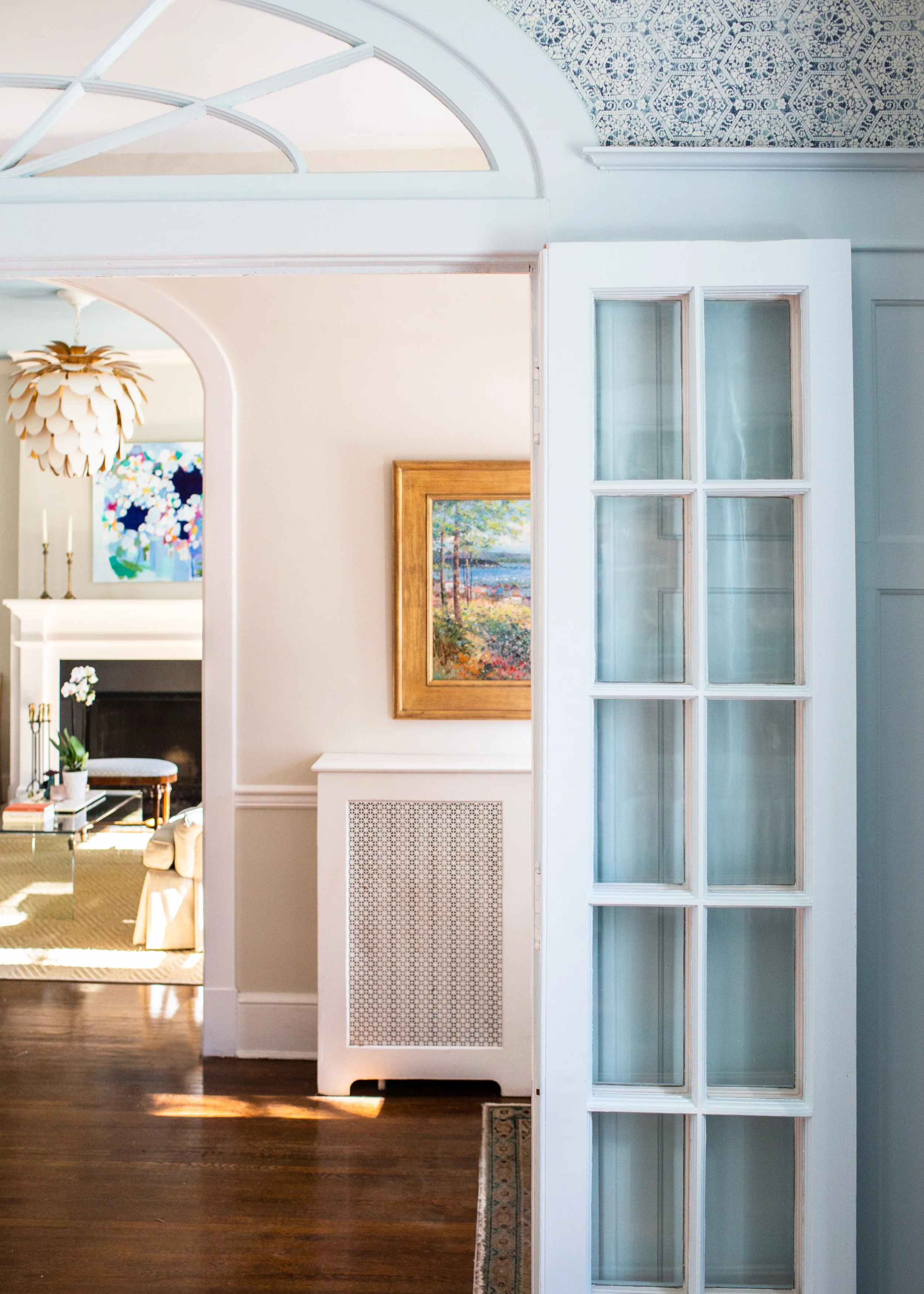 Arched doorway with colorful artwork and a glass-paneled door connecting the home’s interior spaces.