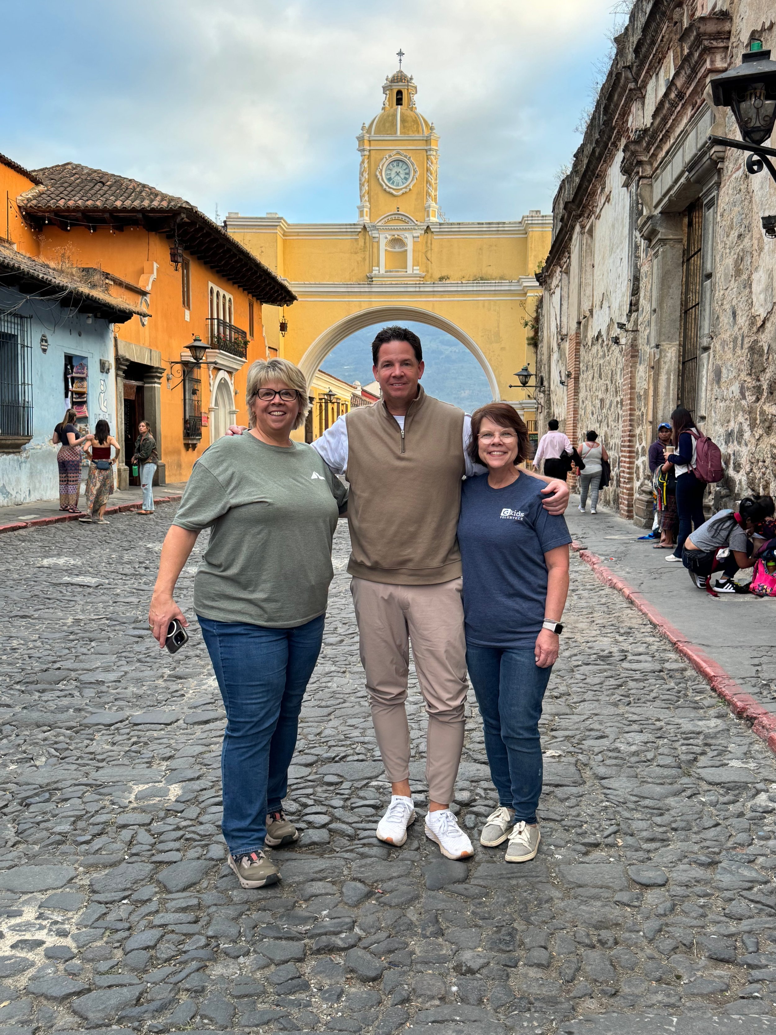 Wes Bowman standing with two women in Antigua, Guatemala, in front of the Santa Catalina Arch.