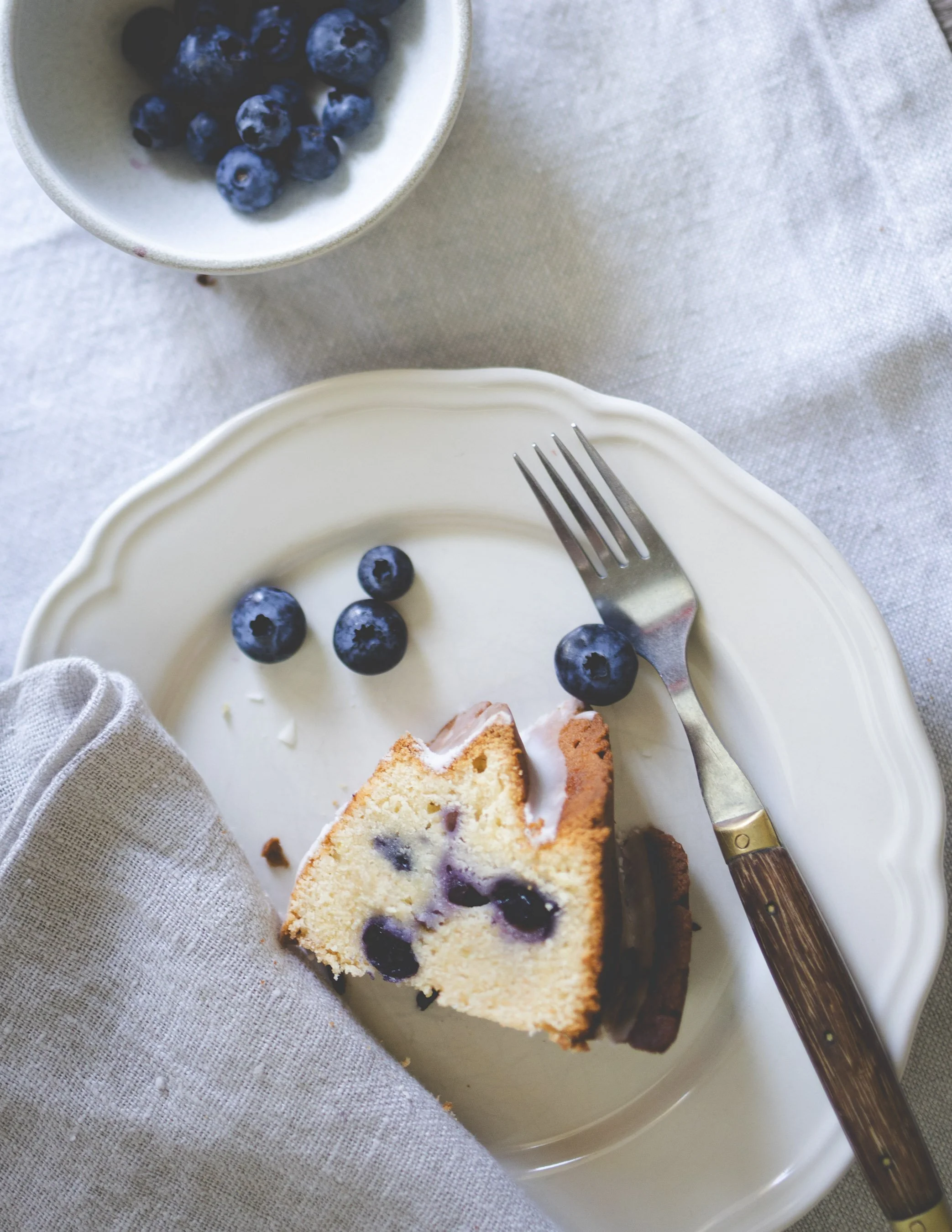 Slice of lemon blueberry sour cream Bundt cake with fresh blueberries and lemon glaze