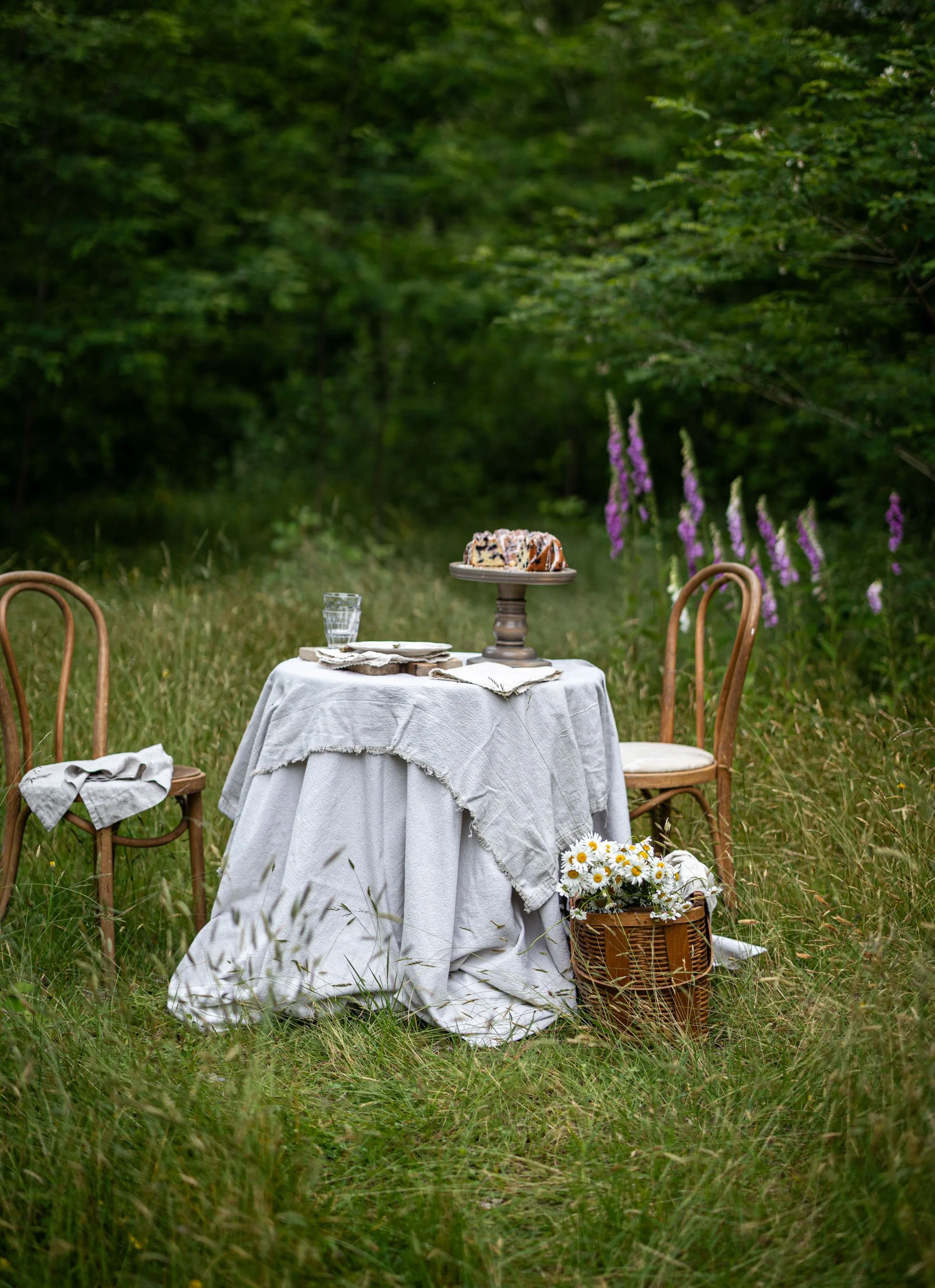 Lemon blueberry sour cream Bundt cake on a romantic summer table surrounded by trees and flowers in a  grassy clearing