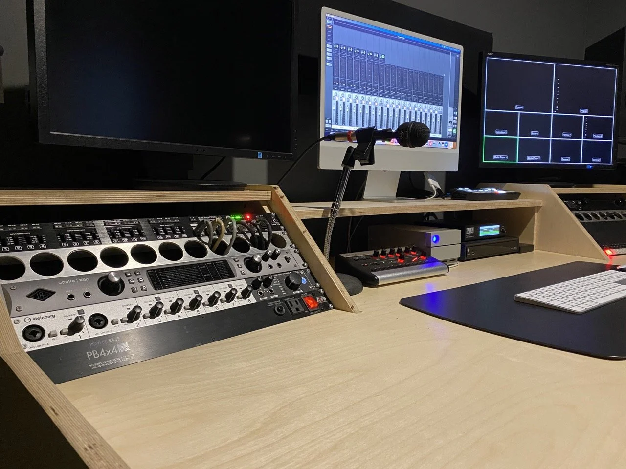 Studio d'enregistrement avec écrans, équipement audio, clavier et microphones.