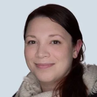 Portrait of a woman with dark hair and a beige scarf smiling gently.