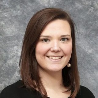 Professional headshot of a smiling woman with brown hair.