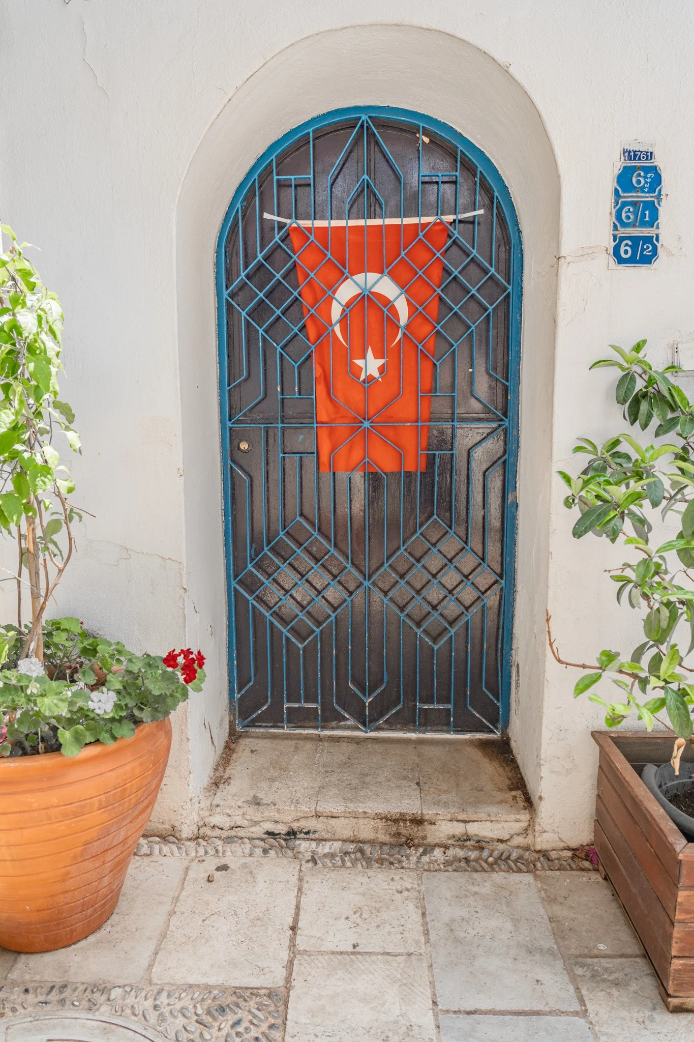 Front door with decorative blue metal gate and Turkish flag hanging in the center