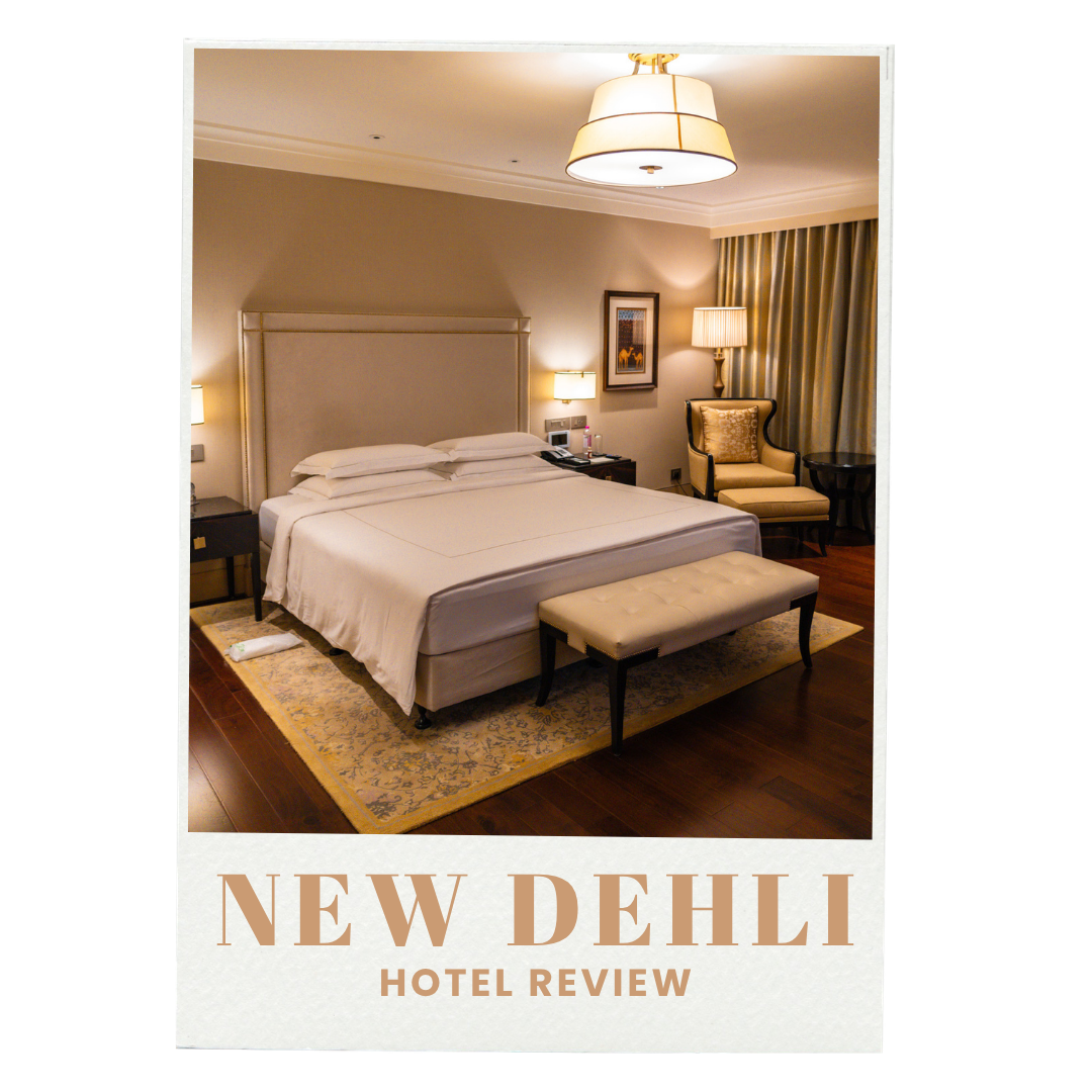 A hotel room with a bed, nightstands, lamps, a chair with a pillow, a bench, curtains, and framed artwork on the wall.
