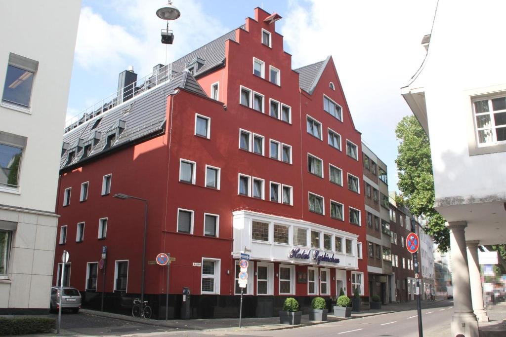 Red multi-story hotel building with white signage, located on a city street, with cars and bicycles parked nearby.