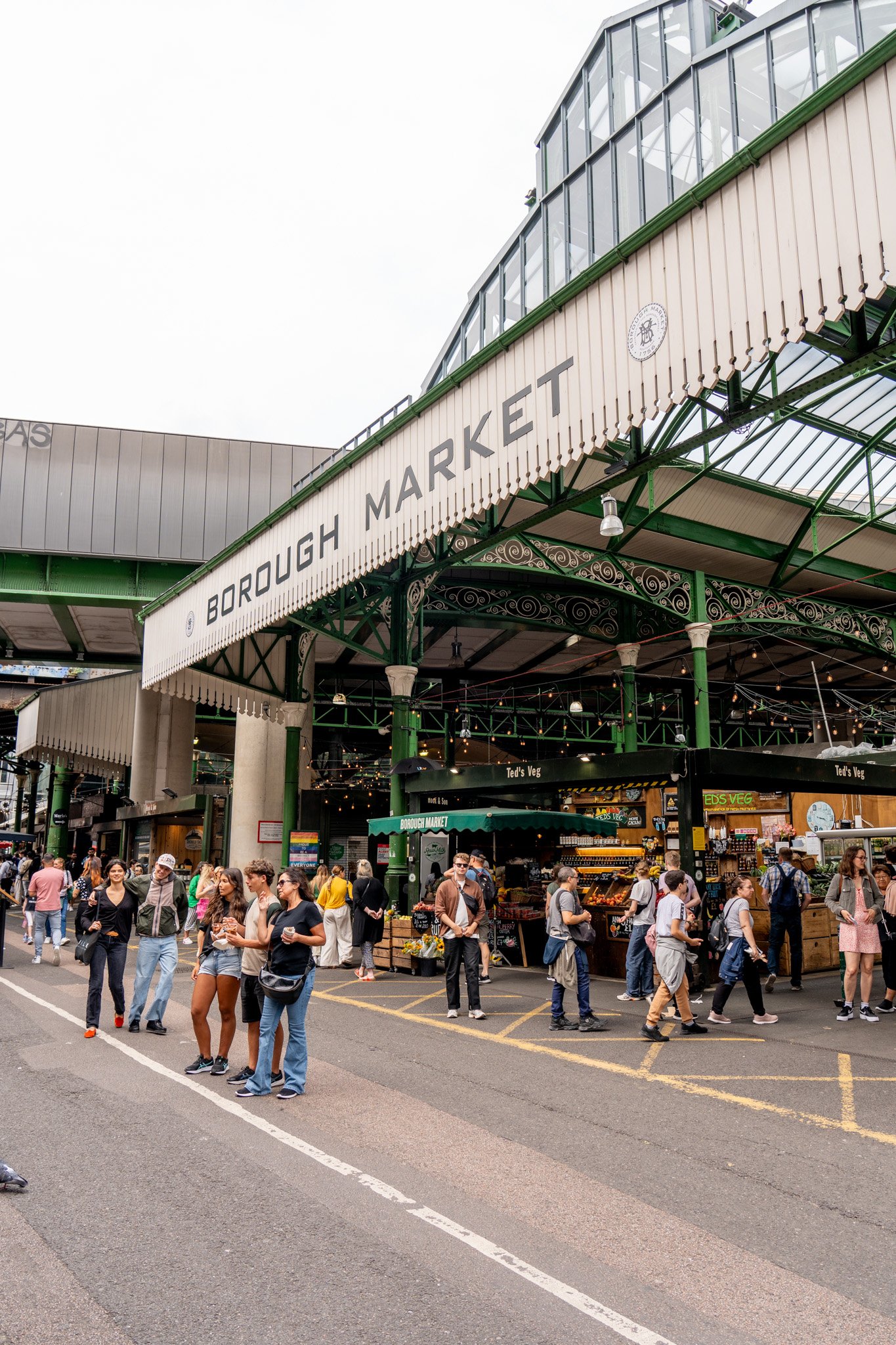 Crowd of people outside Borough Market, a popular food market, with stalls and signage visible.