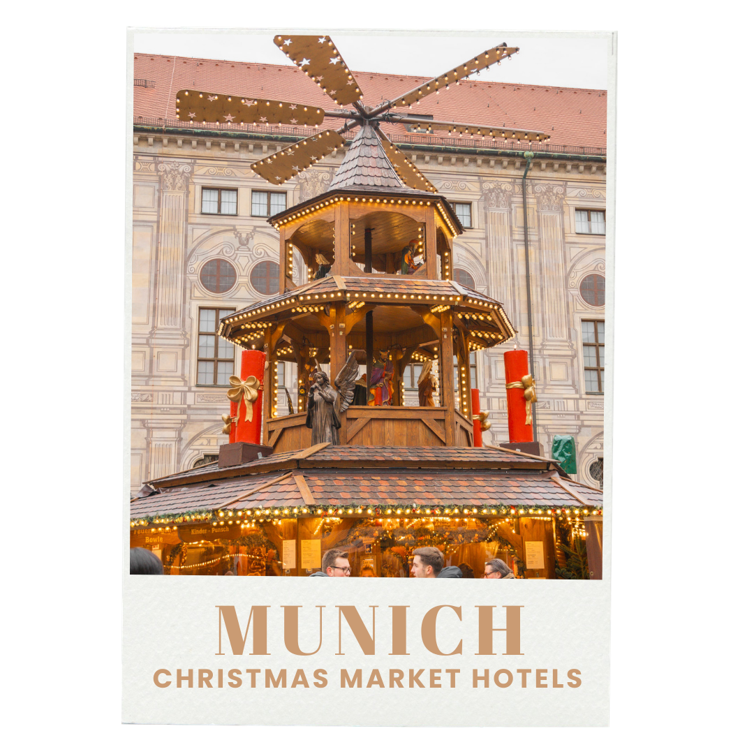 A traditional wooden Christmas pyramid with multiple tiers and spinning figurines, decorated with Christmas lights, set against a historic building at the Munich Christmas Market.