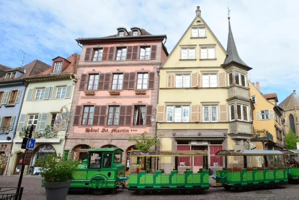 Colorful European buildings with a small green train parked in the foreground.