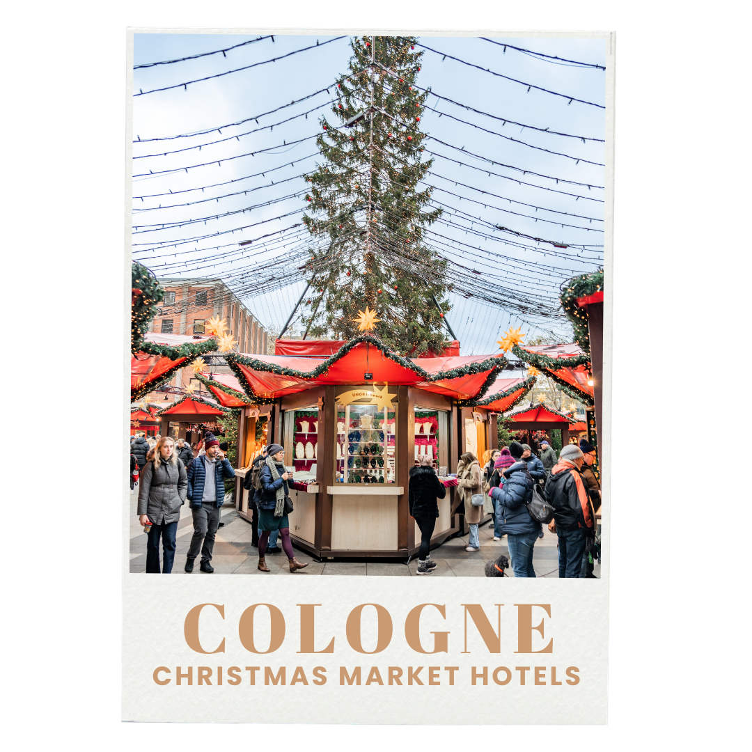 People shopping and walking around a Christmas market in Cologne, with a large decorated Christmas tree in the center and festive lights overhead.