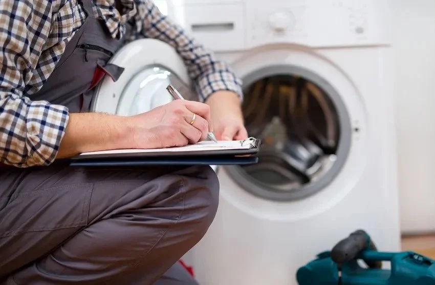 Person with clipboard inspecting a washing machine.